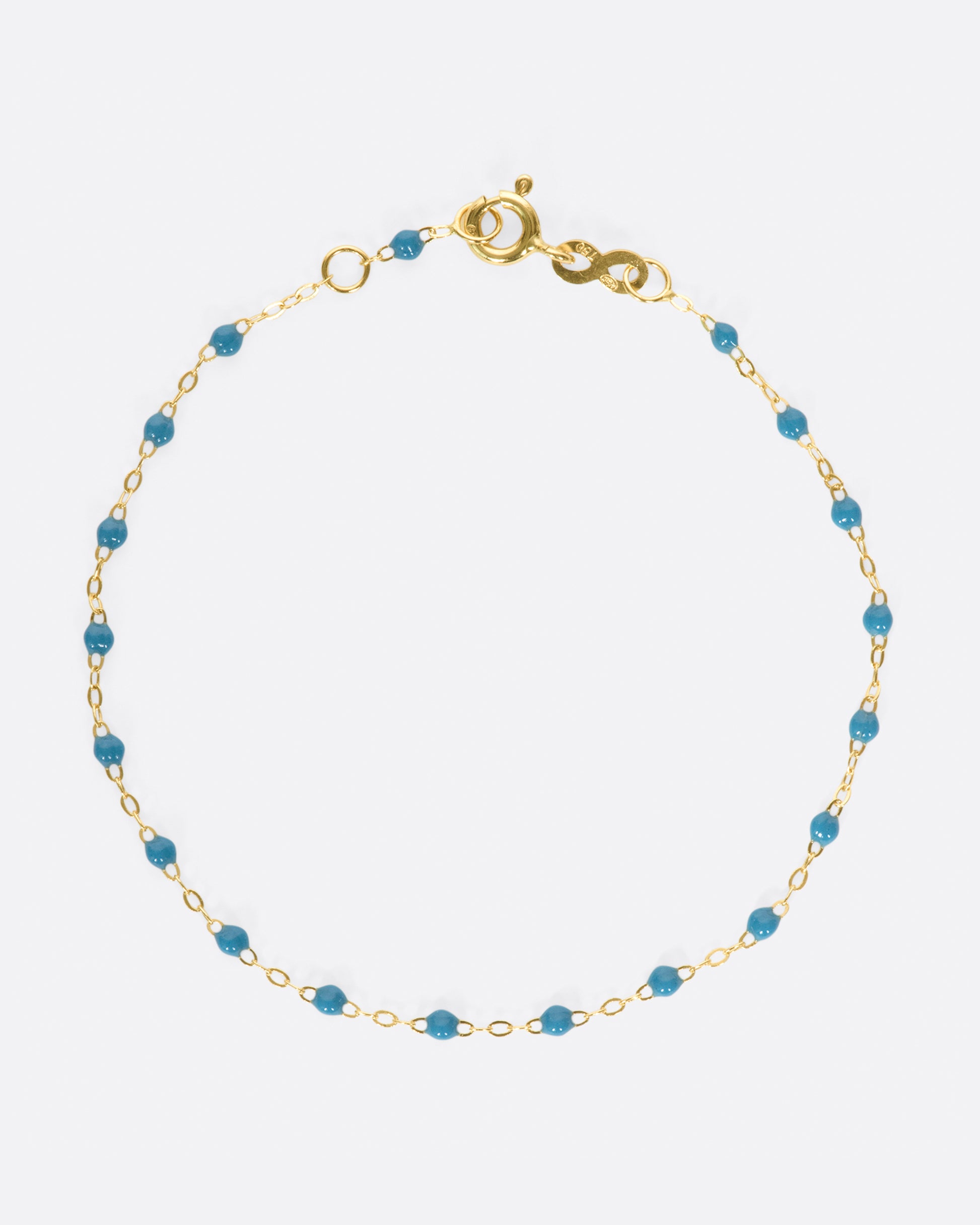 A yellow gold cable chain bracelet with droplets of turquoise resin. Shown closed from the top.
