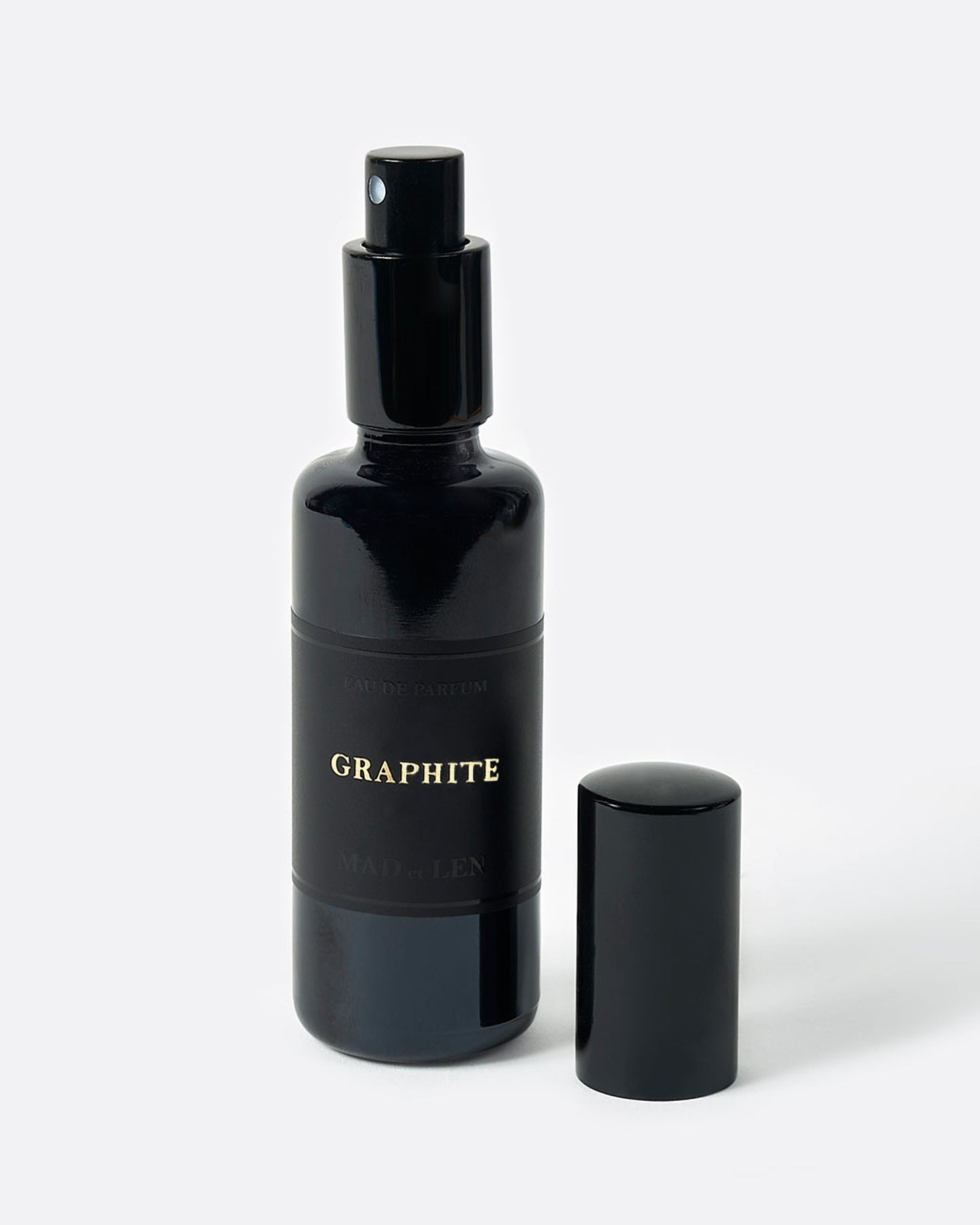 A black perfume bottle with a spray top and GRAPHITE in gold letters on its black label. A black cap sits next to it. Shown from the front.