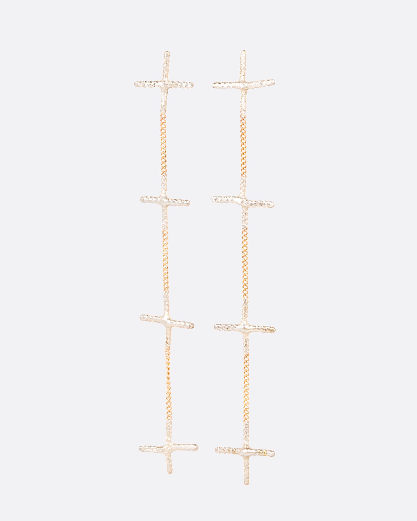 A pair of long earrings with four silver crosses and yellow gold chain in an alternating pattern. Shown from the front.