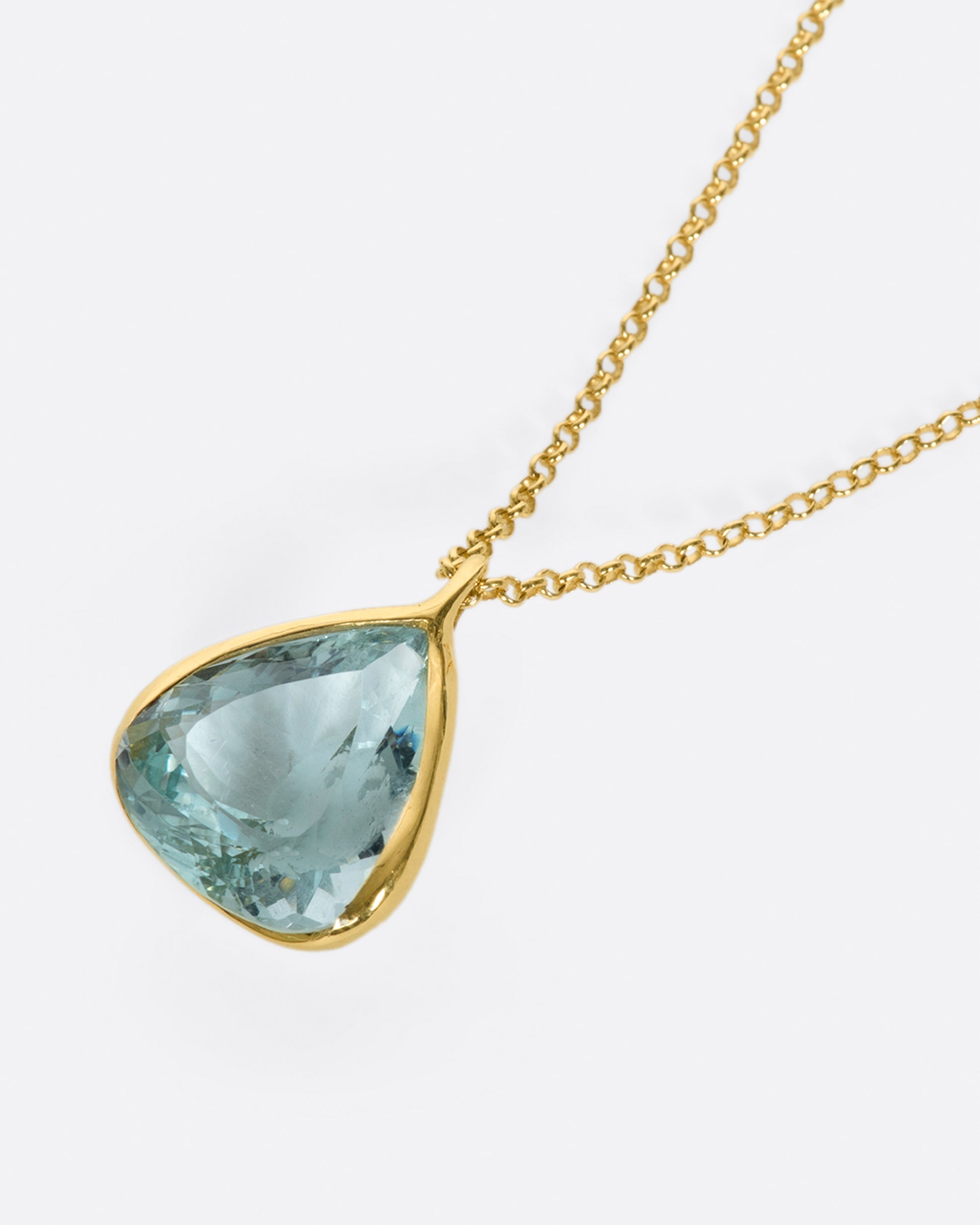 A yellow gold cable chain necklace with a large triangular aquamarine pendant