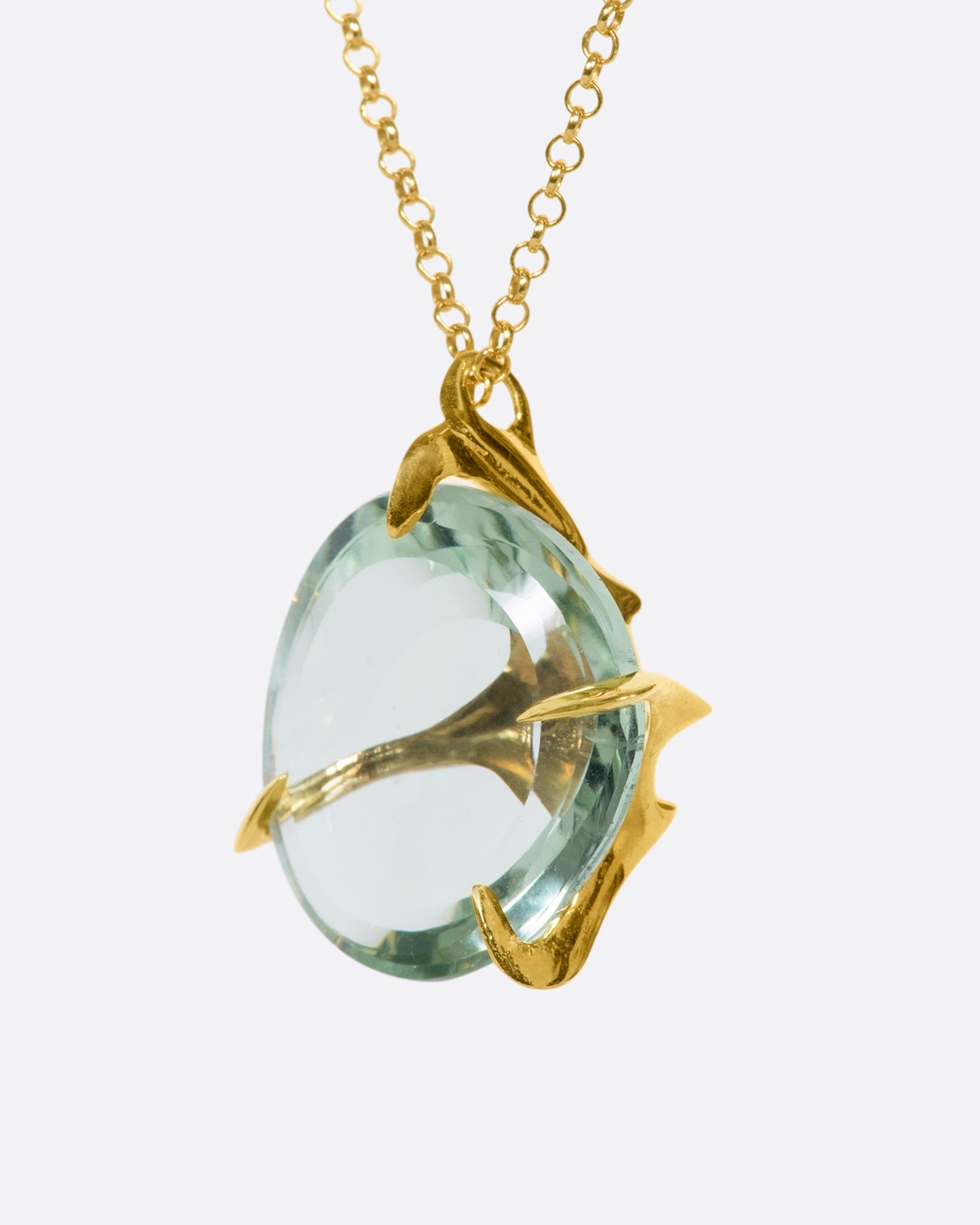 A yellow gold chain necklace with a large, round green quartz pendant set in large gold prongs.