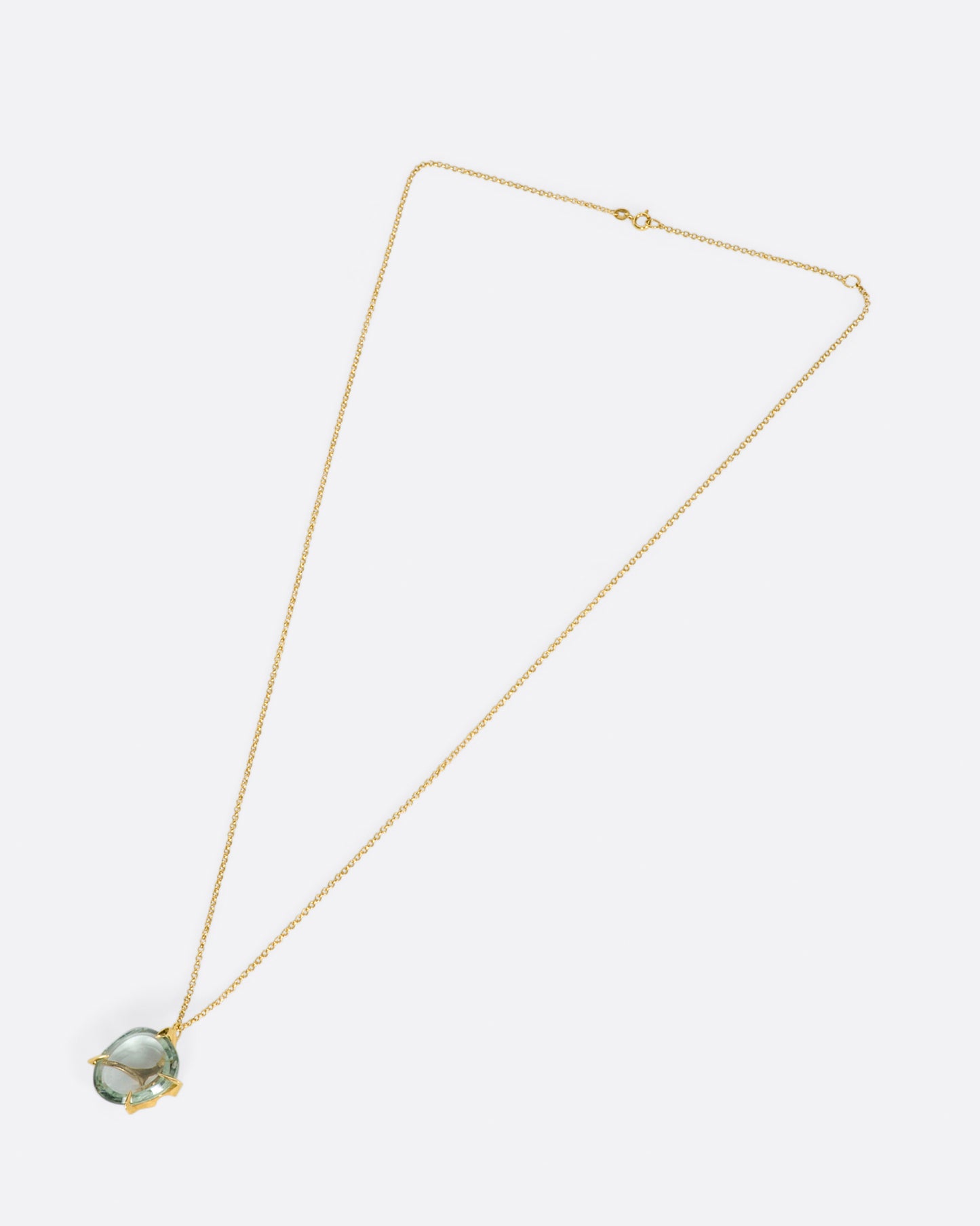 A yellow gold chain necklace with a large, round green quartz pendant set in large gold prongs.