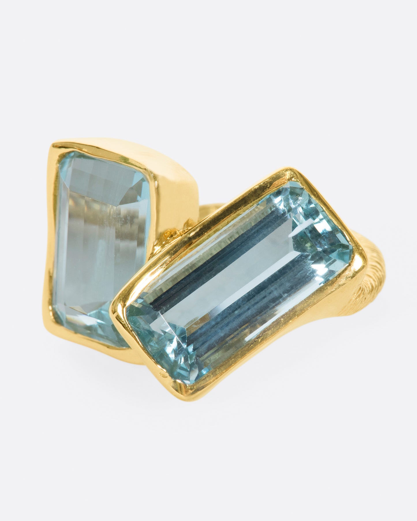 A yellow gold ring featuring two large emerald cut aquamarines set slightly askew