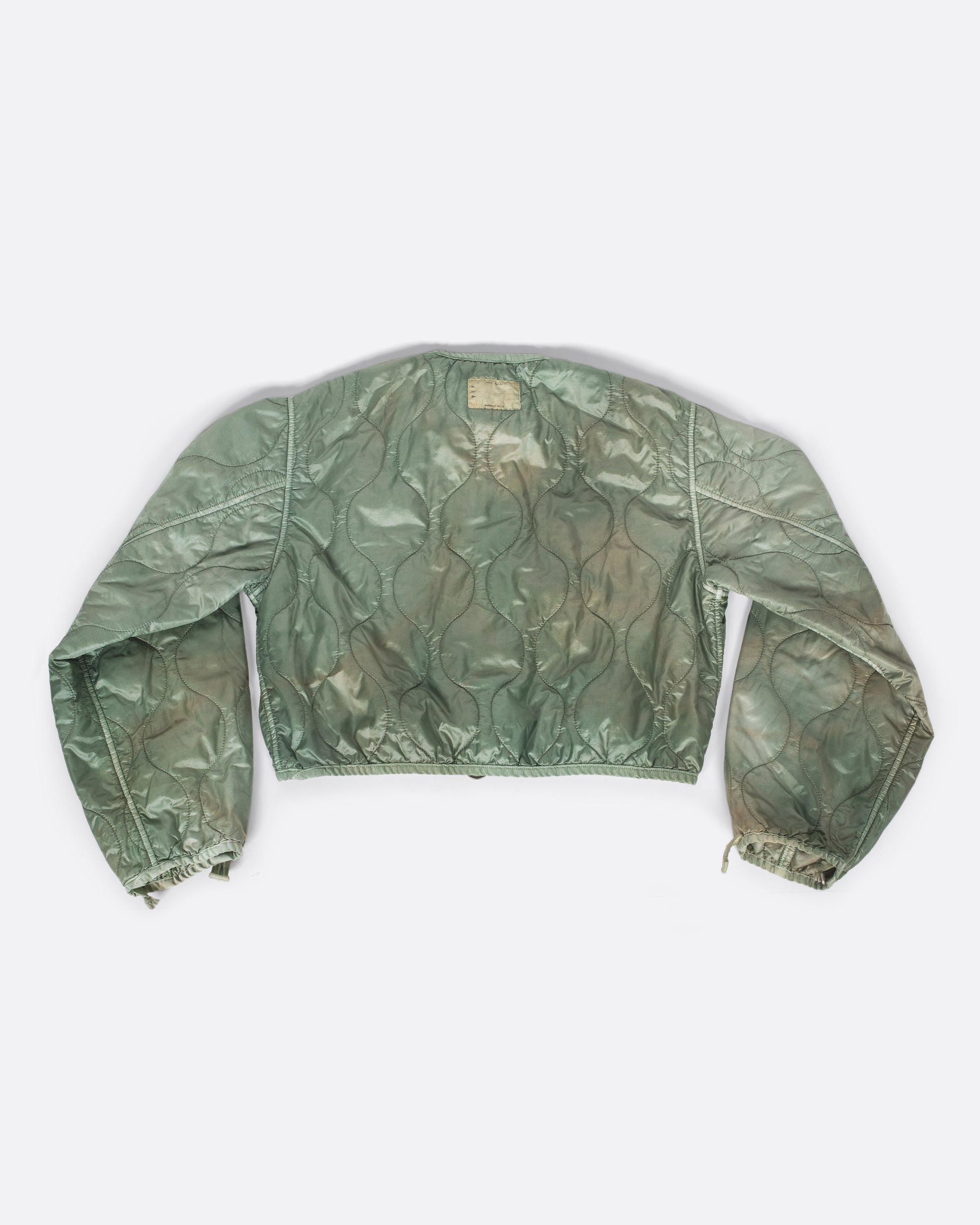 A nylon, quilted, dip-dyed bolero jacket in a muted sage green - great for layering!