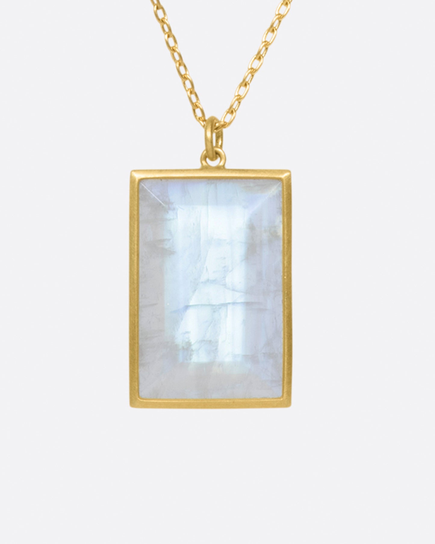 A large rainbow moonstone glows in a narrow matte gold bezel on this pendant necklace.