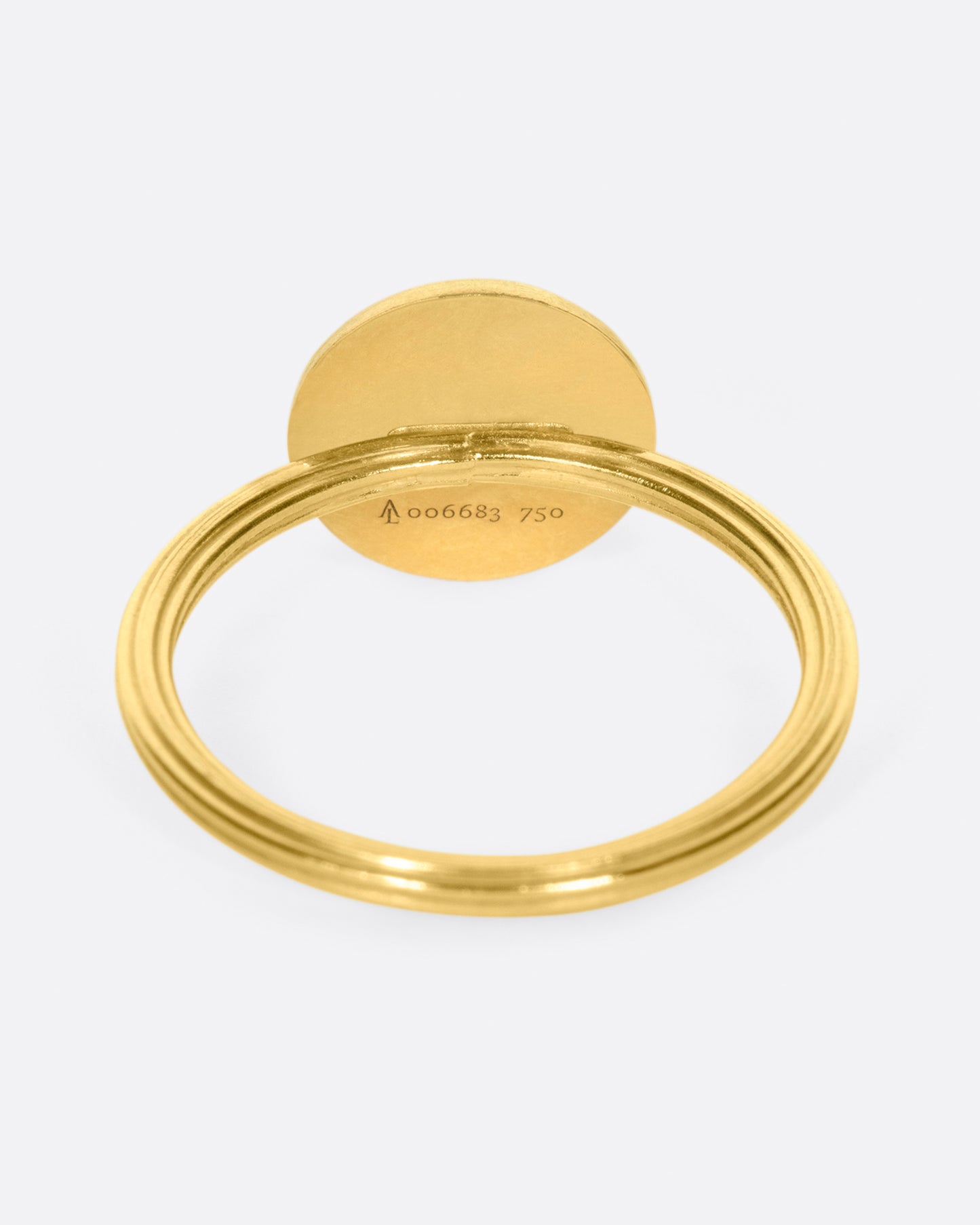 A yellow gold ring with a round moon face with diamond eyes. Shown from the back.