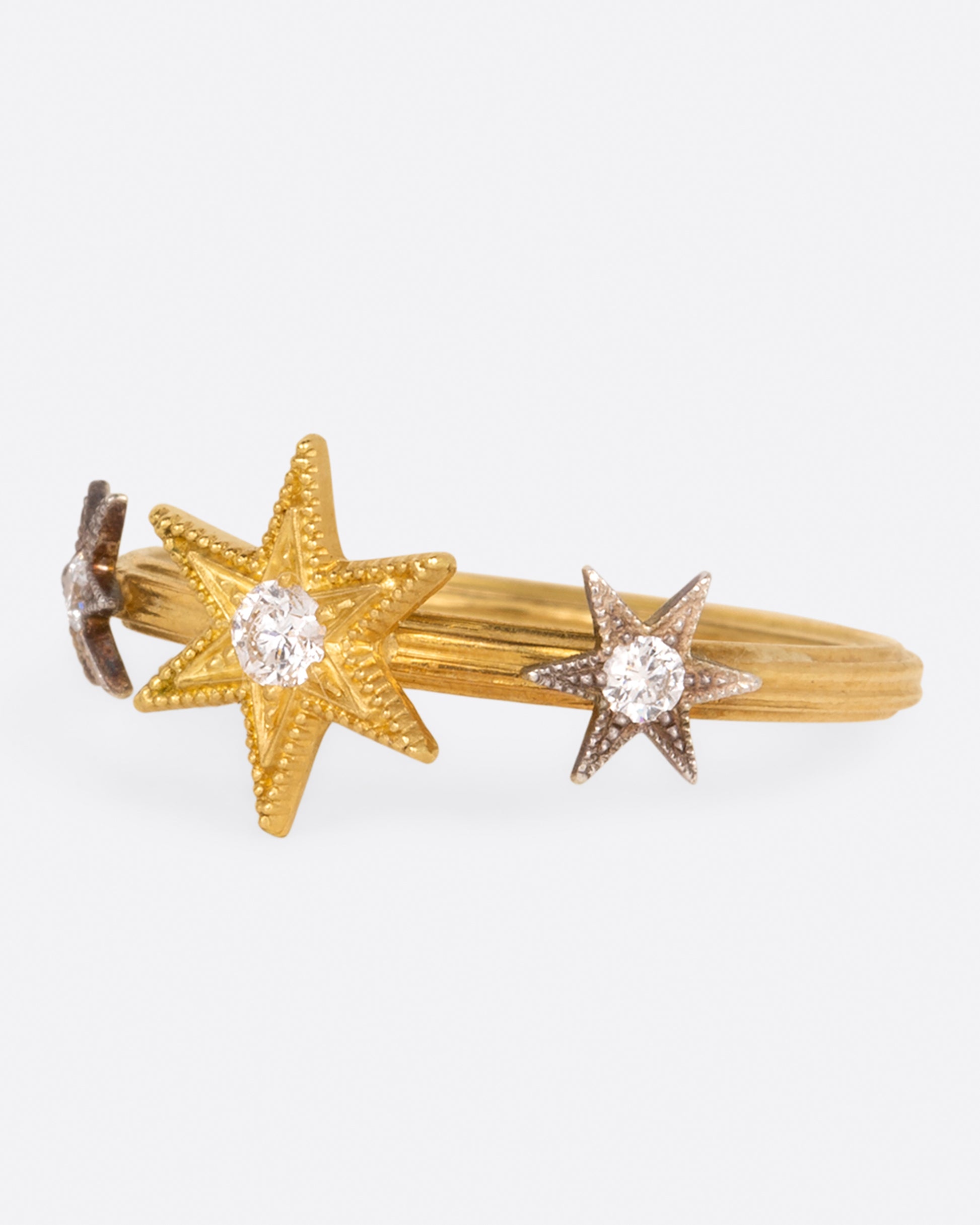 This ring features three millgrain stars; two platinum and one yellow gold, all dotted with diamonds.