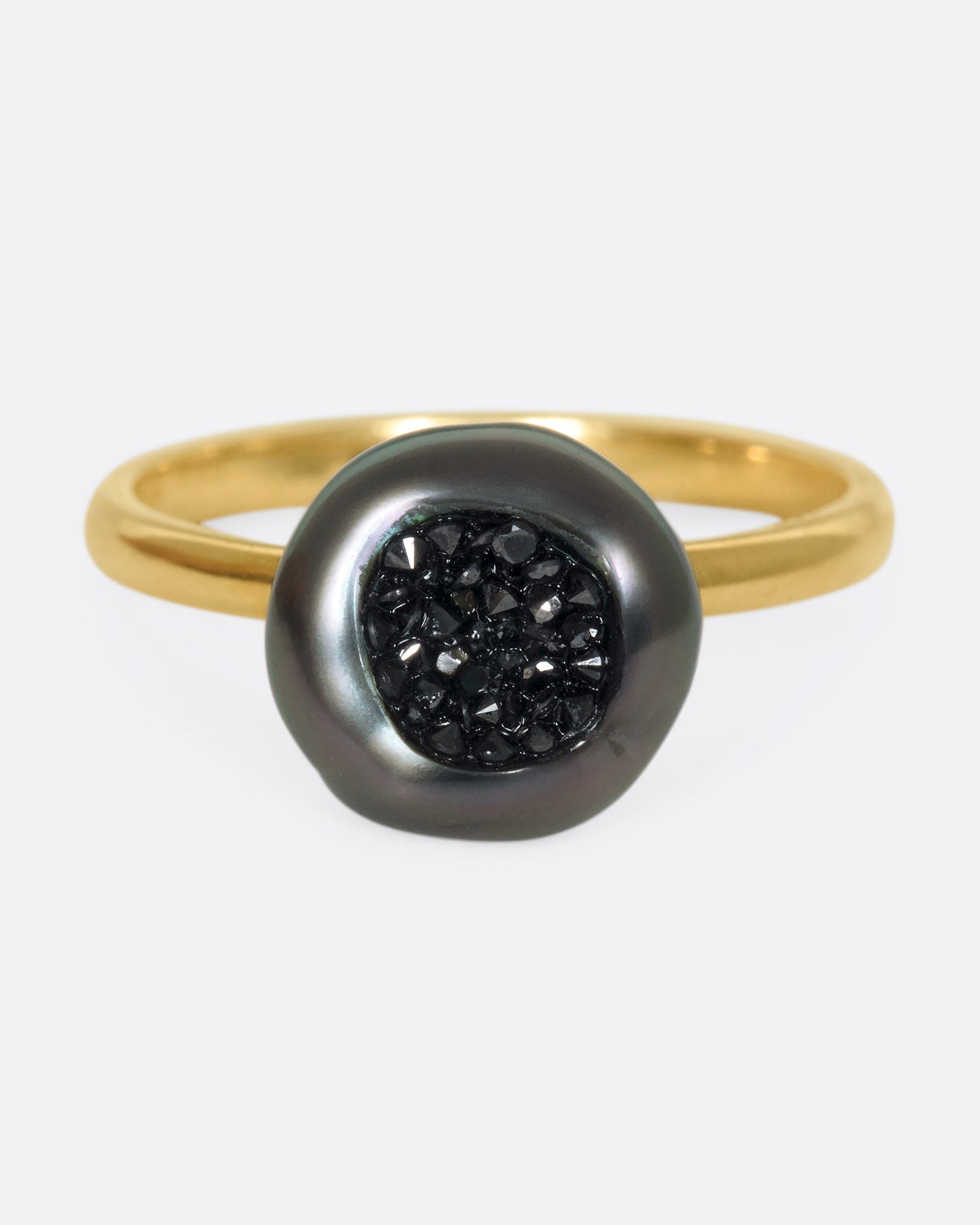 A 14k gold band with a carved Tahitian keshi pearl lined with black diamonds