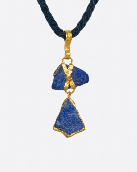 Two pieces of organic, untreated Afghan lapis wrapped in high karat gold, hanging on an adjustable blue cord.