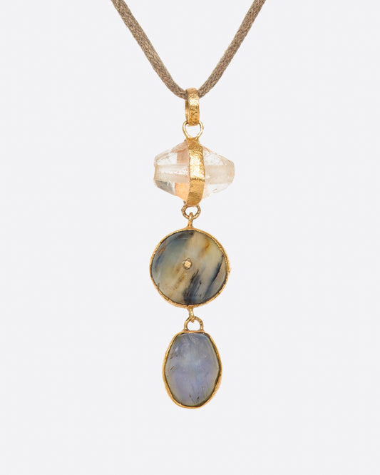 A high karat gold pendant with quartz, labradorite, and sapphire components.
