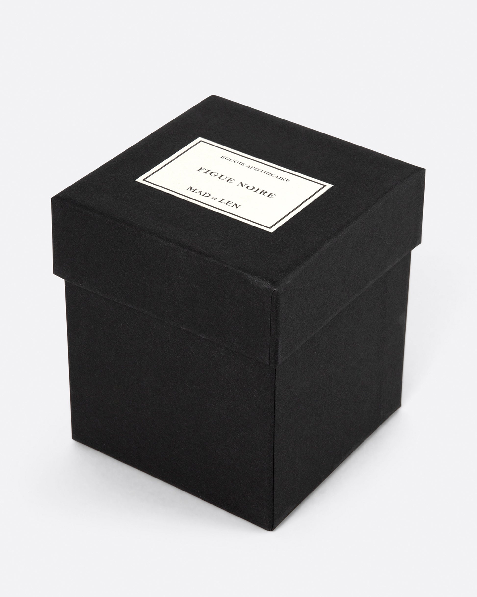 A square black Mad et Len Figue Noire candle box shown from the side at an angle.