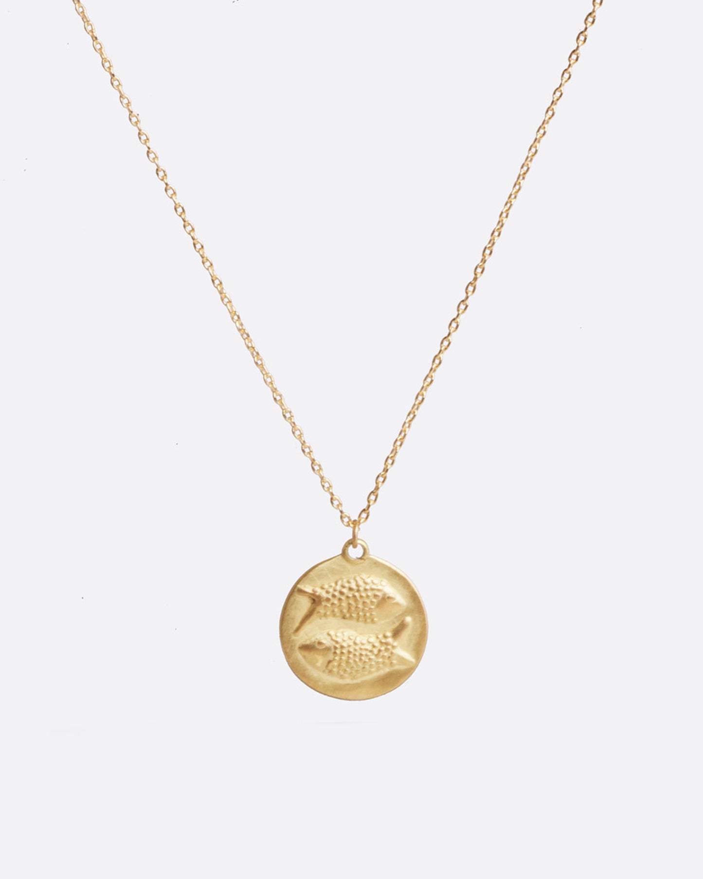 A yellow gold necklace with a round pendant with your choice of zodiac symbol.