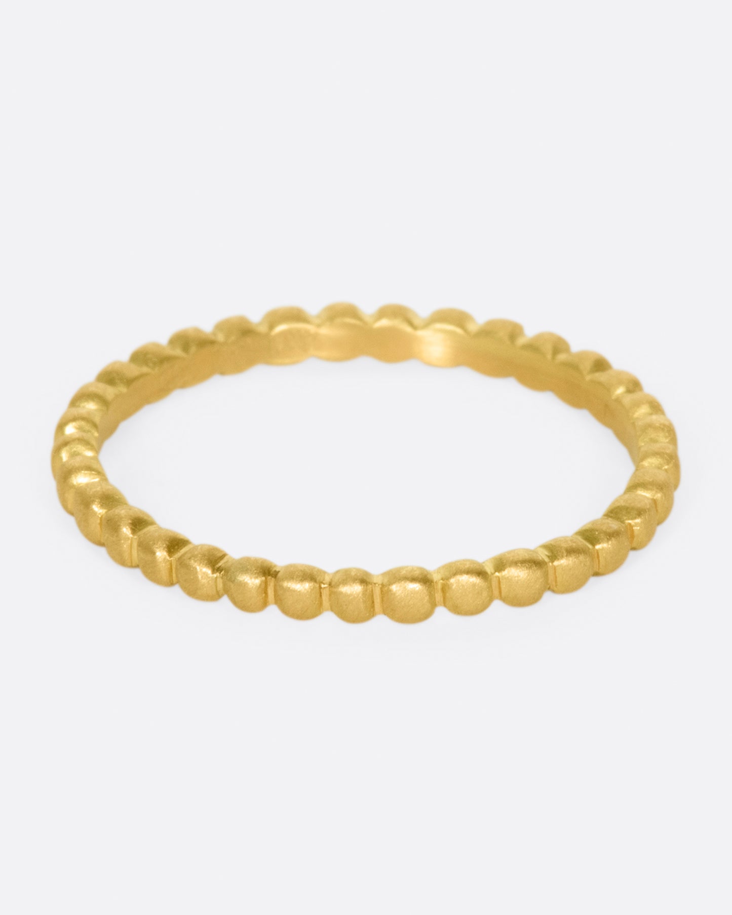 A matte gold eternity band made from dots of gold.