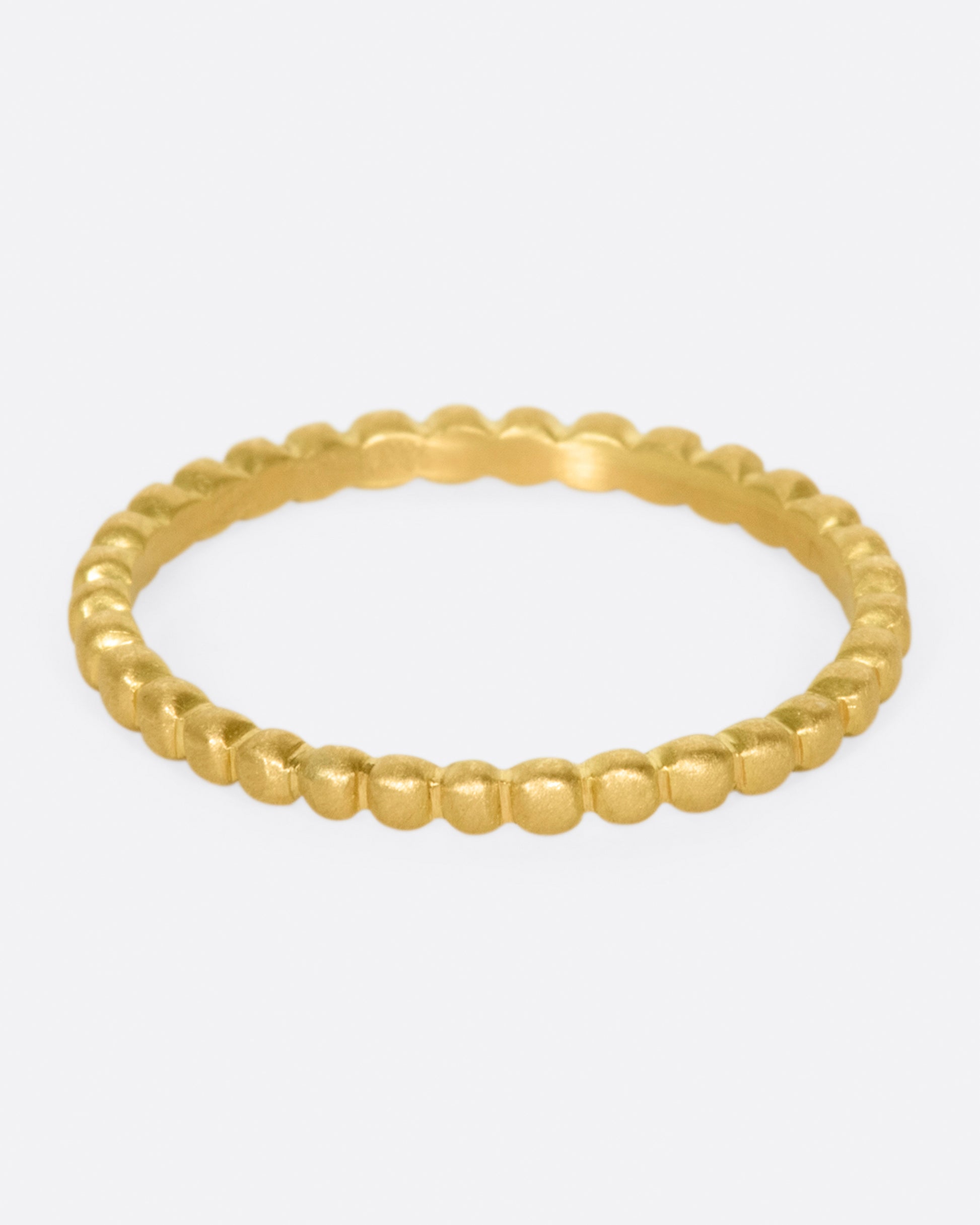 A matte gold eternity band made from dots of gold.