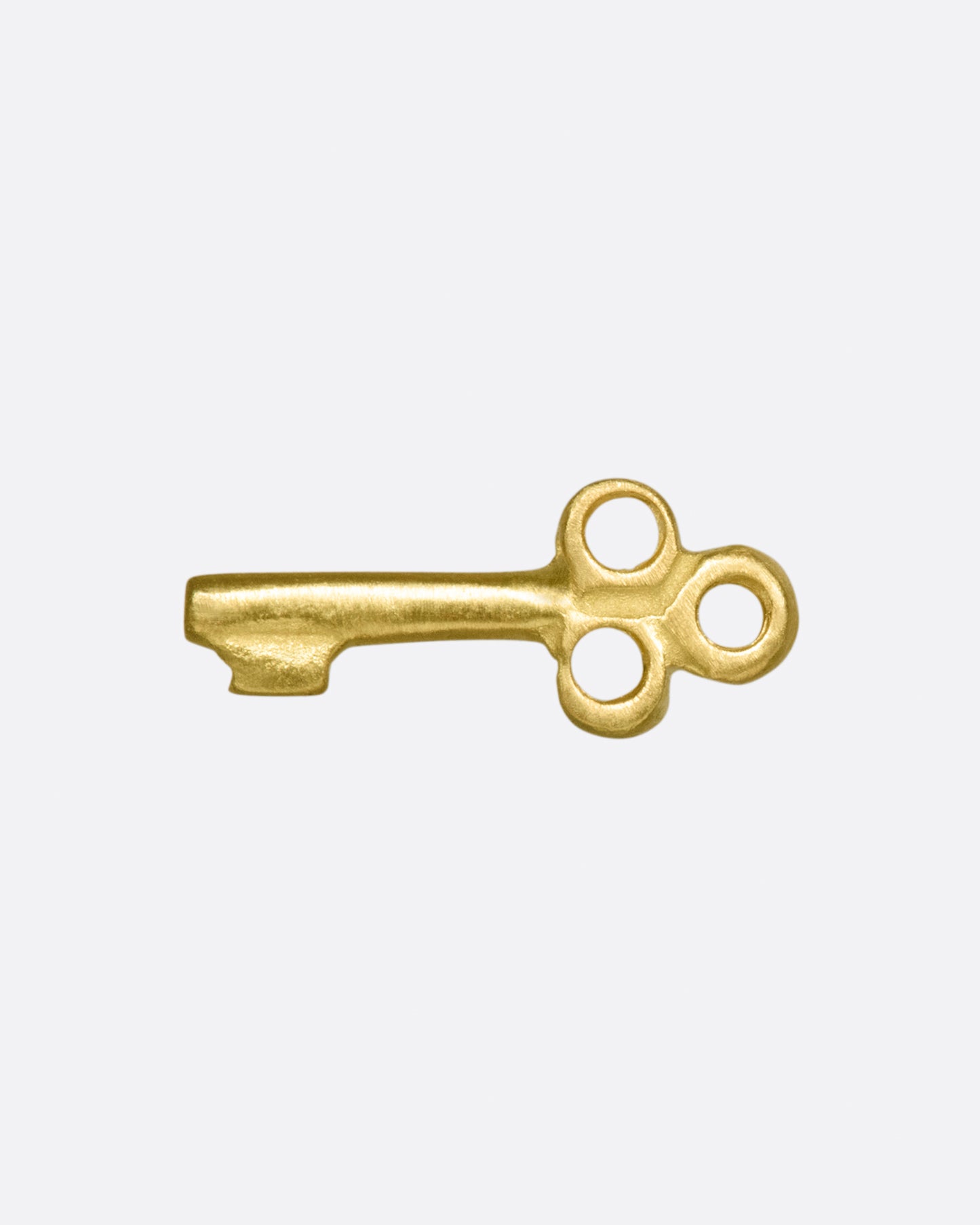 A tiny, matte gold key to adorn your ear.