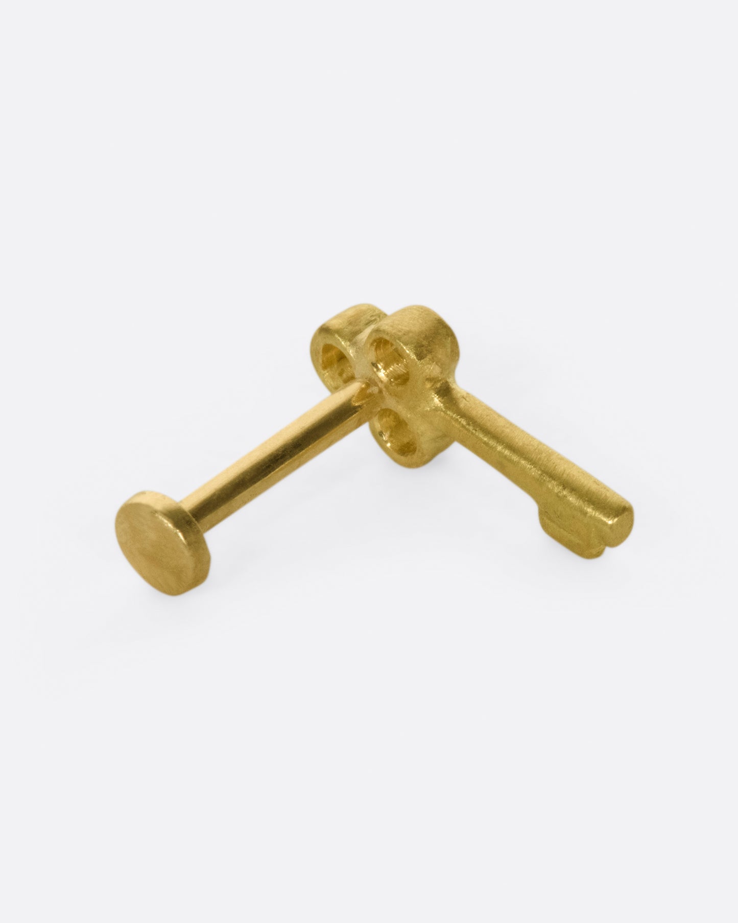 A tiny, matte gold key to adorn your ear.