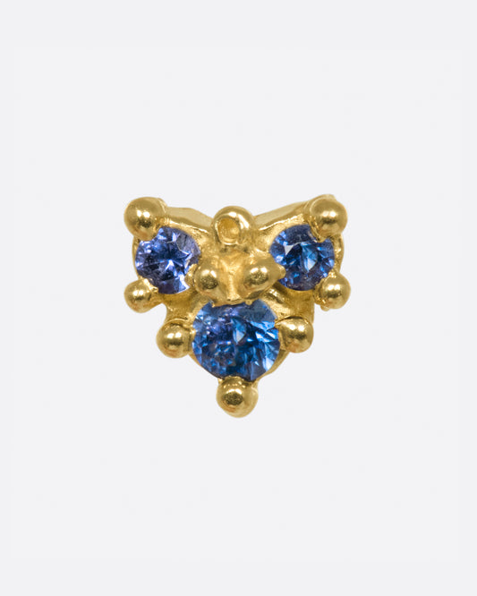 An arrow-like shape with three blue sapphires set in hand formed prongs.
