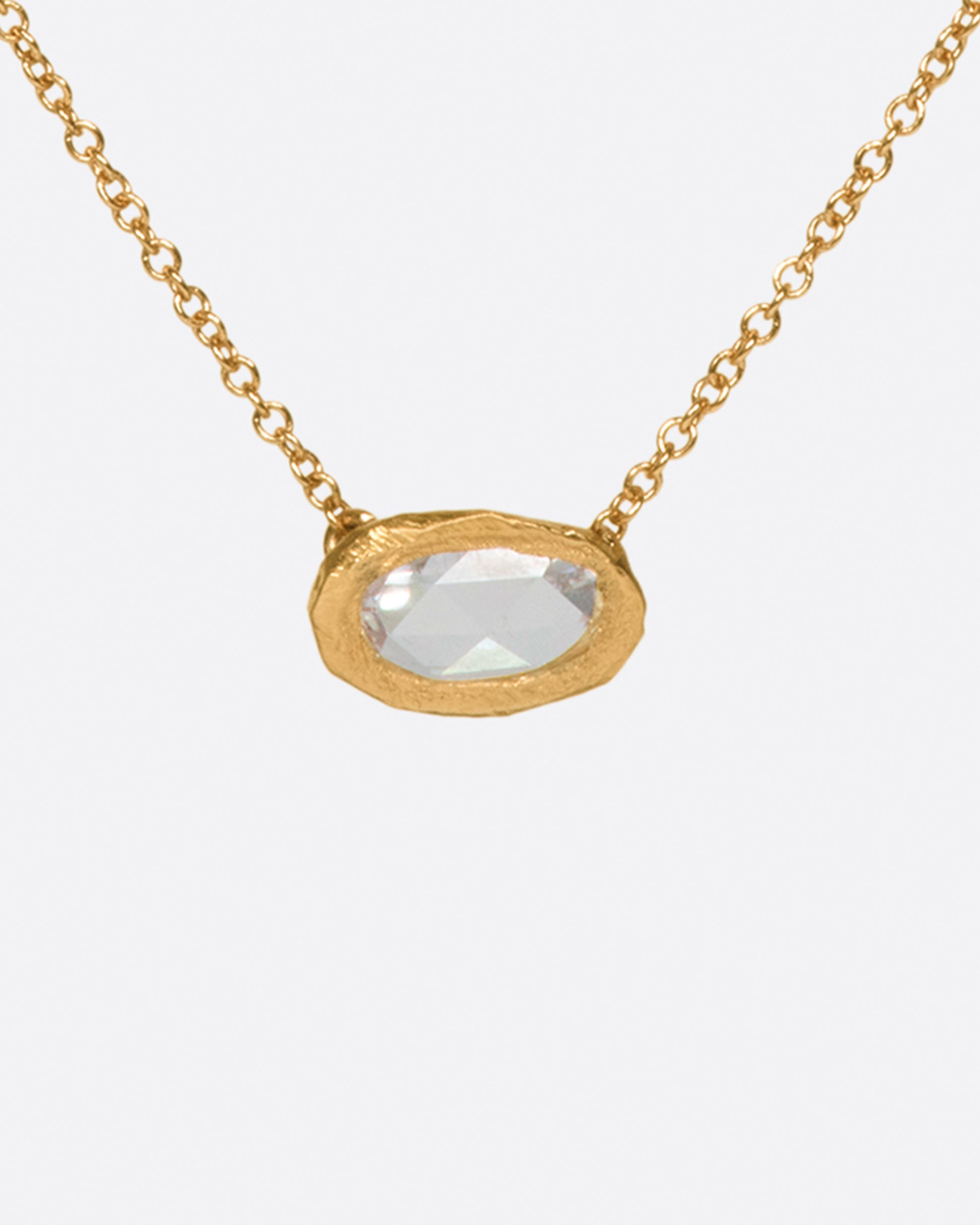 A rose gold hand carved bezel pendant containing an east-west rose cut diamond on a cable chain. Shown from the front.