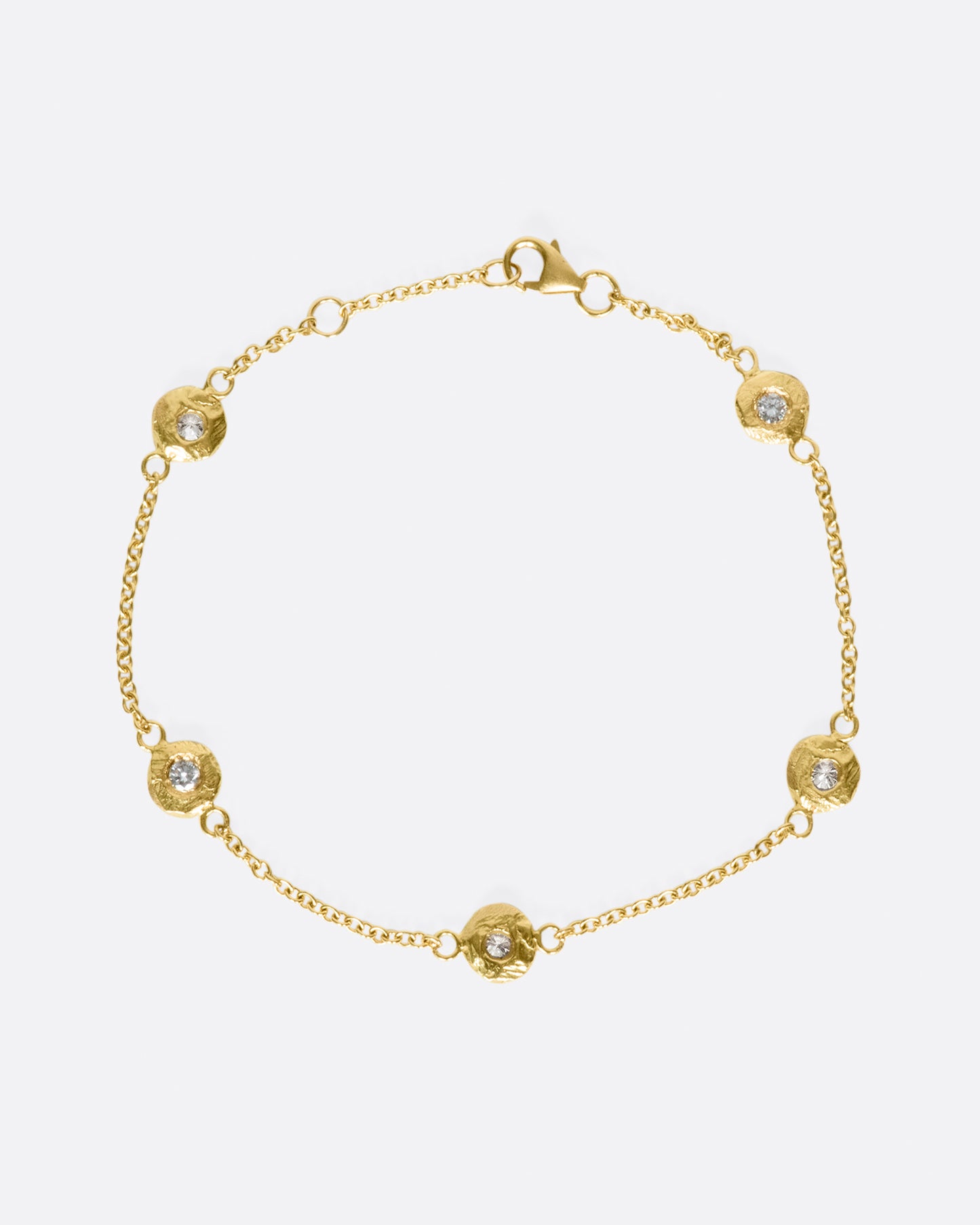 A handmade take on a classic style; this chain bracelet has five diamonds set in hand carved bezels, a bit over an inch apart.