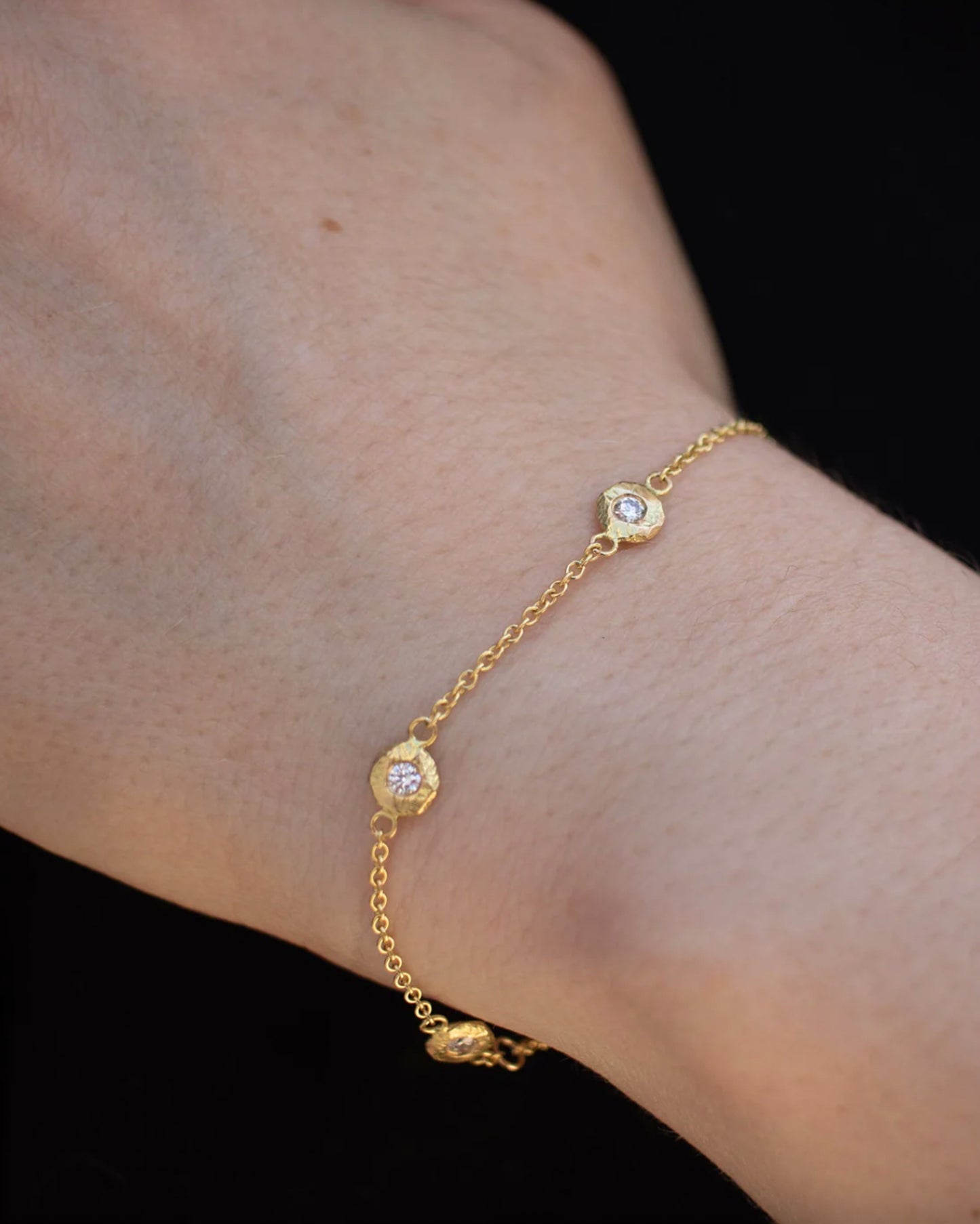A handmade take on a classic style; this chain bracelet has five diamonds set in hand carved bezels, a bit over an inch apart.