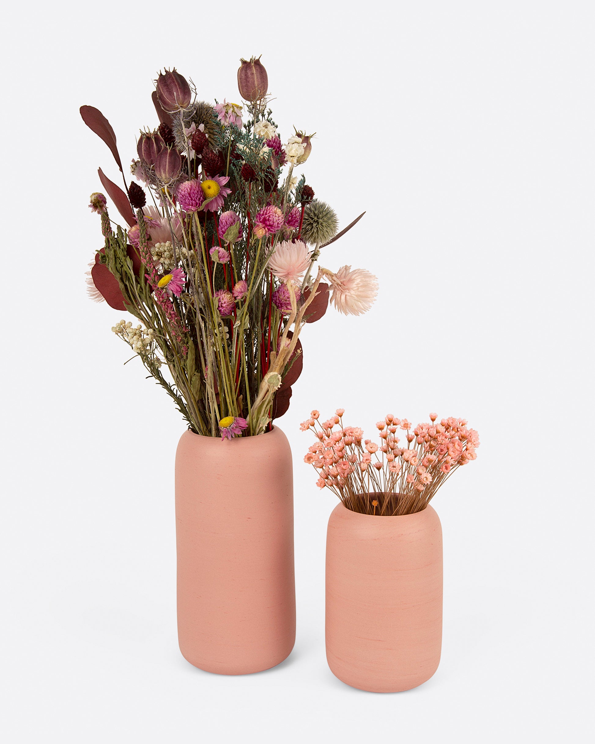 Two pink porcelain vases with flower arrangements, one small and one large. Shown from the front.