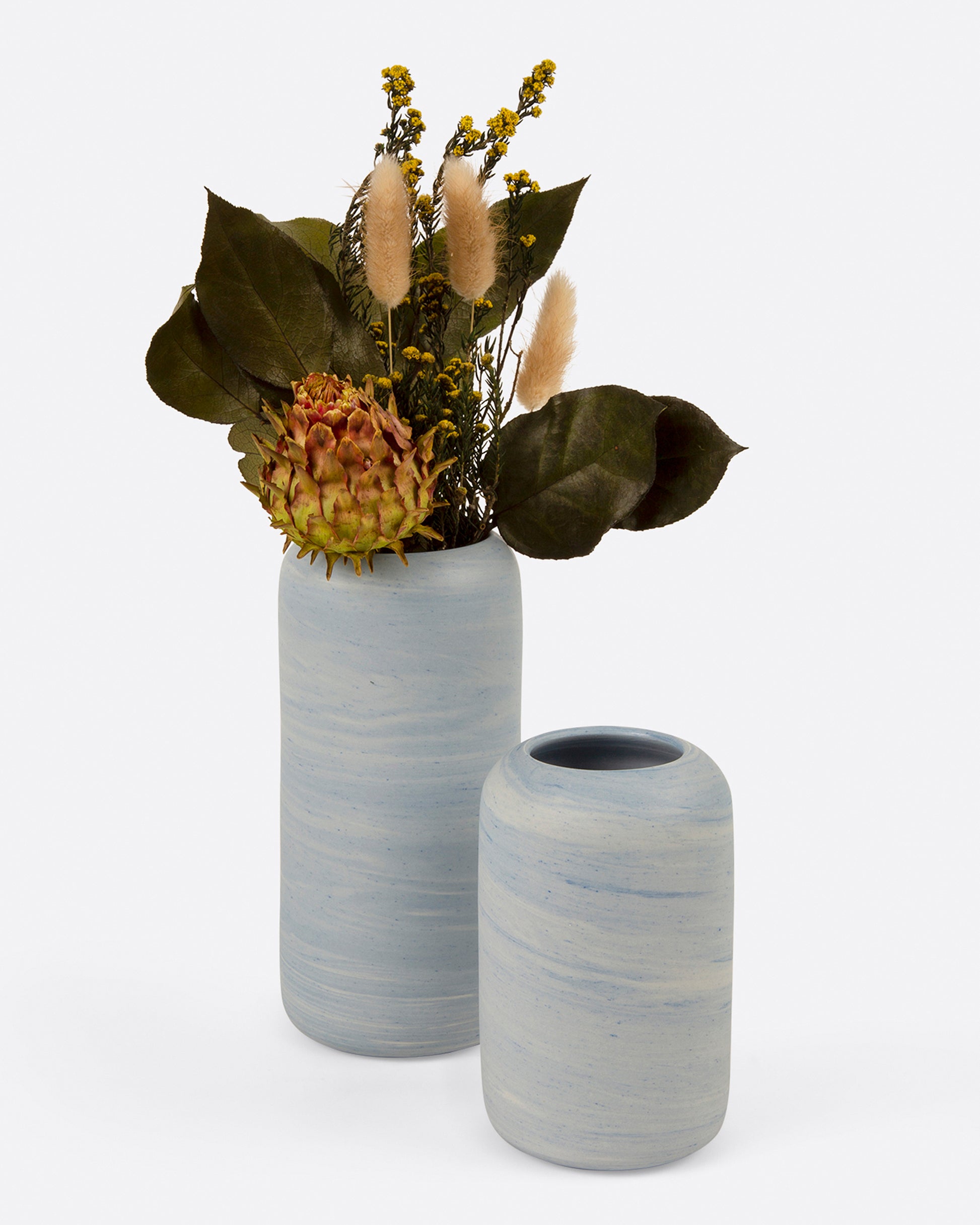 Two marbled blue and white porcelain vases, one small and one large, the larger with a floral arrangement. Shown from the front.