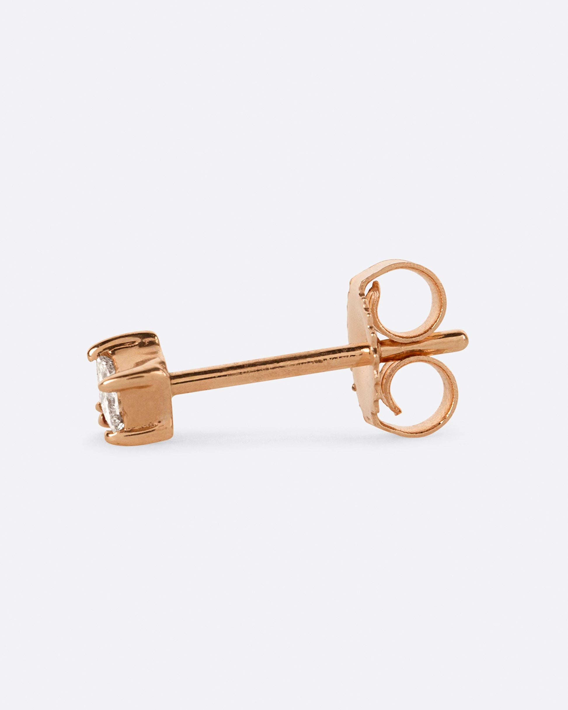 A yellow gold stud earring with a princess cut diamond and a round pink sapphire. View from the side.