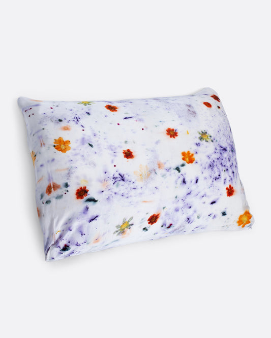 A pillow shown with a purple and orange flower dotted silk pillowcase.