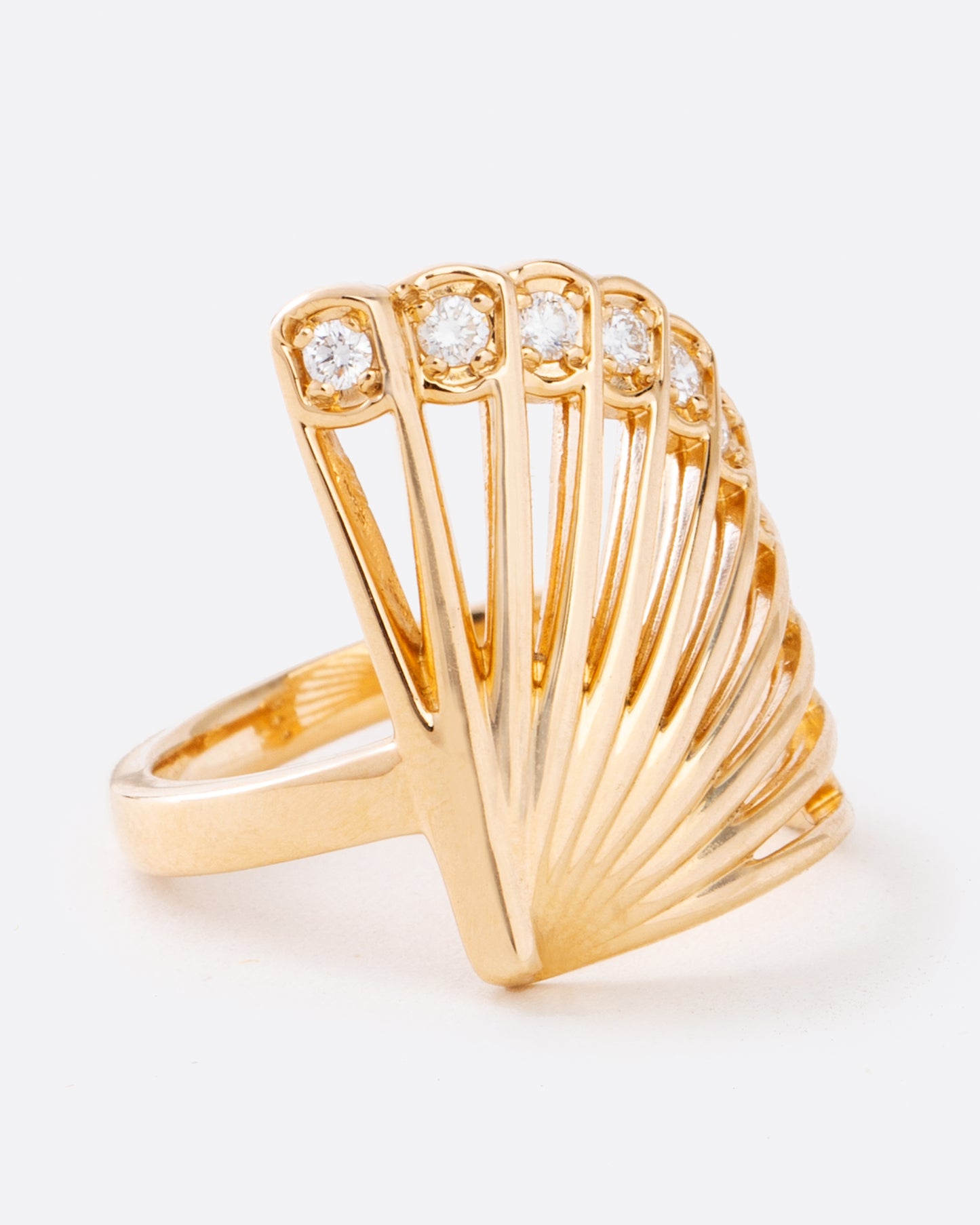 A yellow gold ring in the shape of a fan with diamonds along the top edge. Shown from the side.