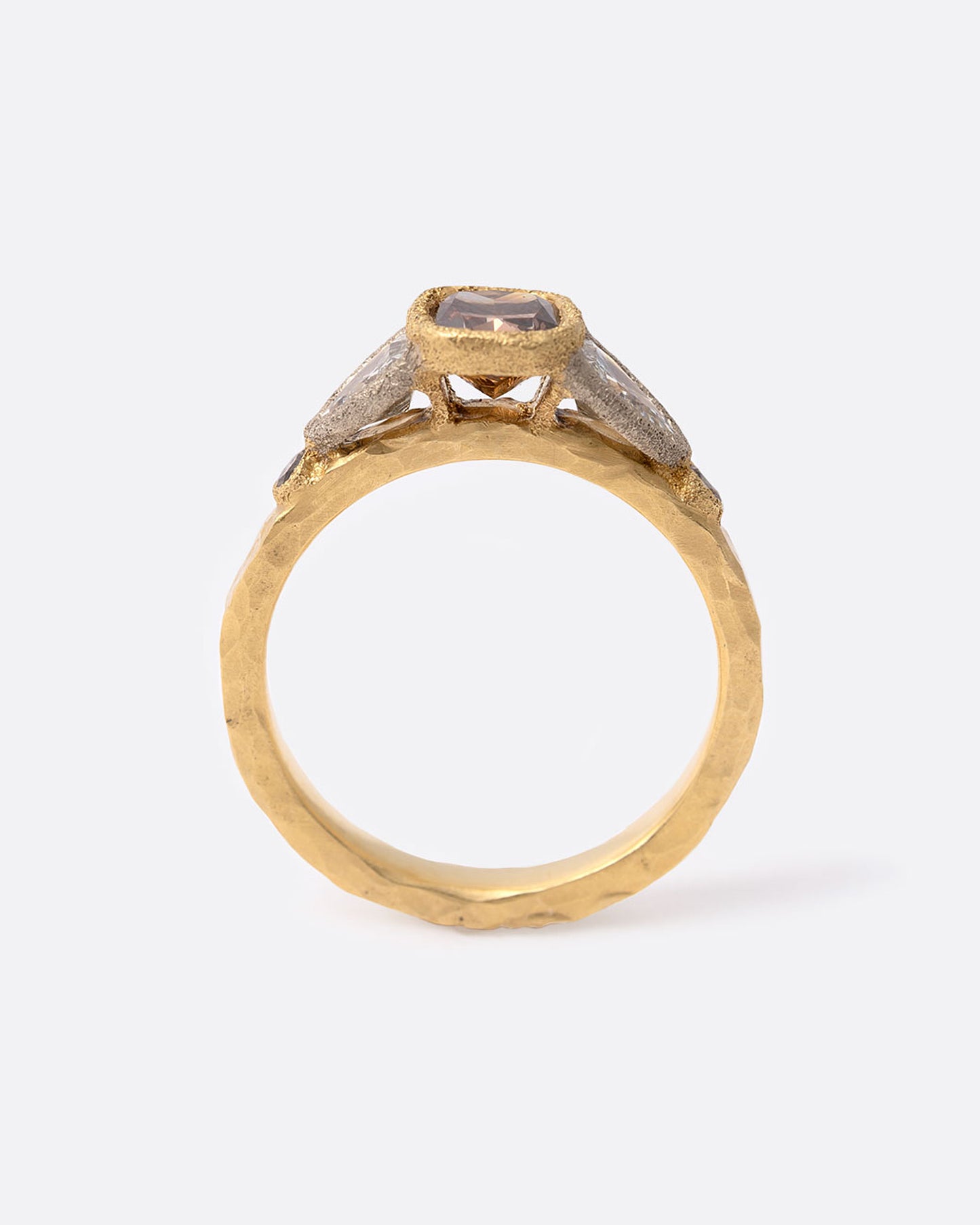 1A yellow gold ring with a cushion cut cognac diamond at the center flanked by two shield cut diamonds and two smaller round cognac diamonds. Shown standing up from the side.