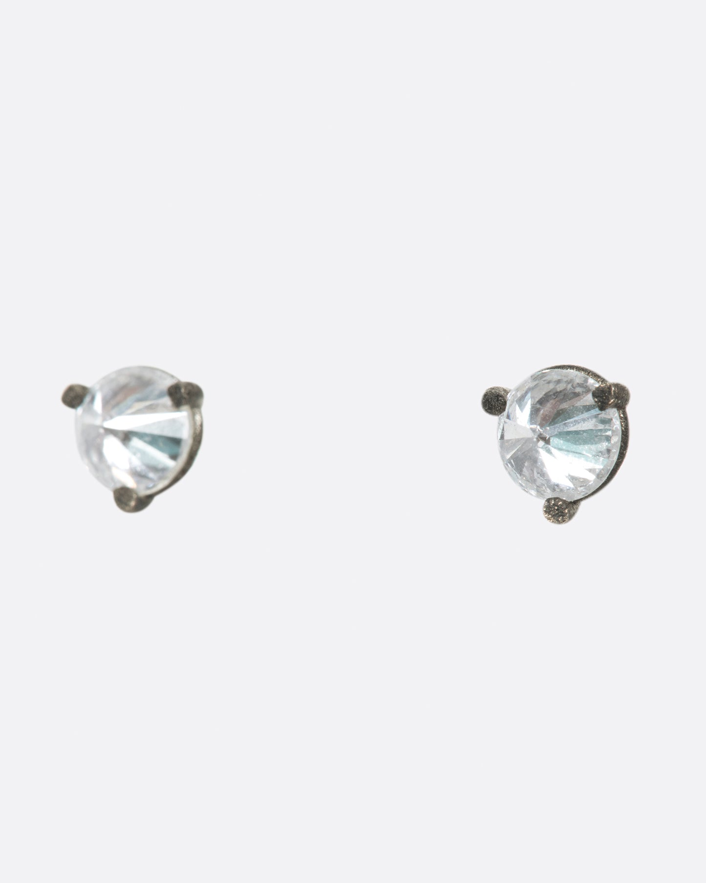 A pair of solitaire stud earrings with round inverted diamonds set in darkened white gold settings.