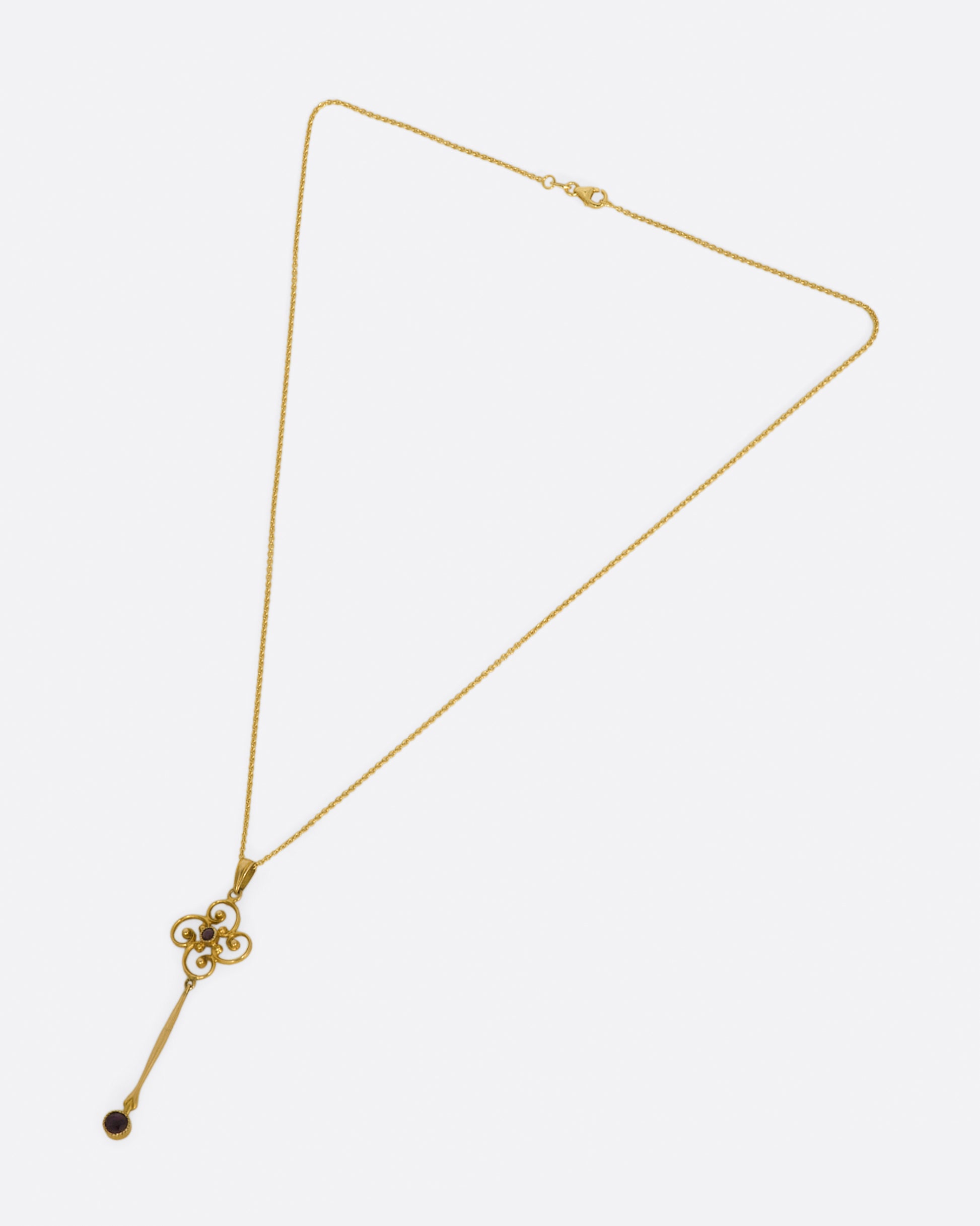 A contemporary yellow gold chain necklace with a vintage yellow gold pendant. The pendant has a flower-like design at the top with with a long bar hanging from it, and a round amethyst at the bottom.