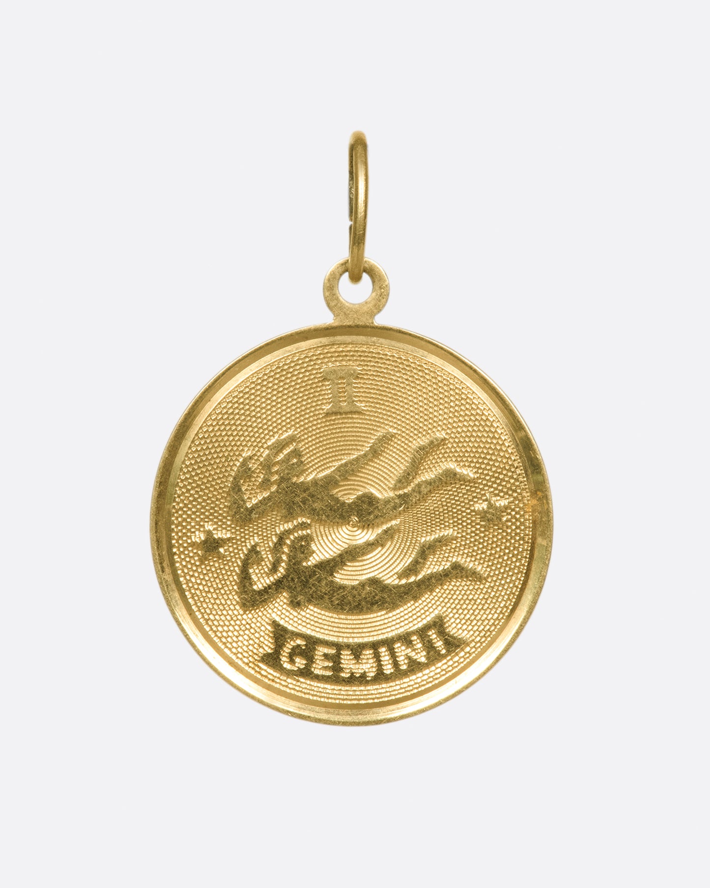An engine turned zodiac pendant with a blank, polished backside.