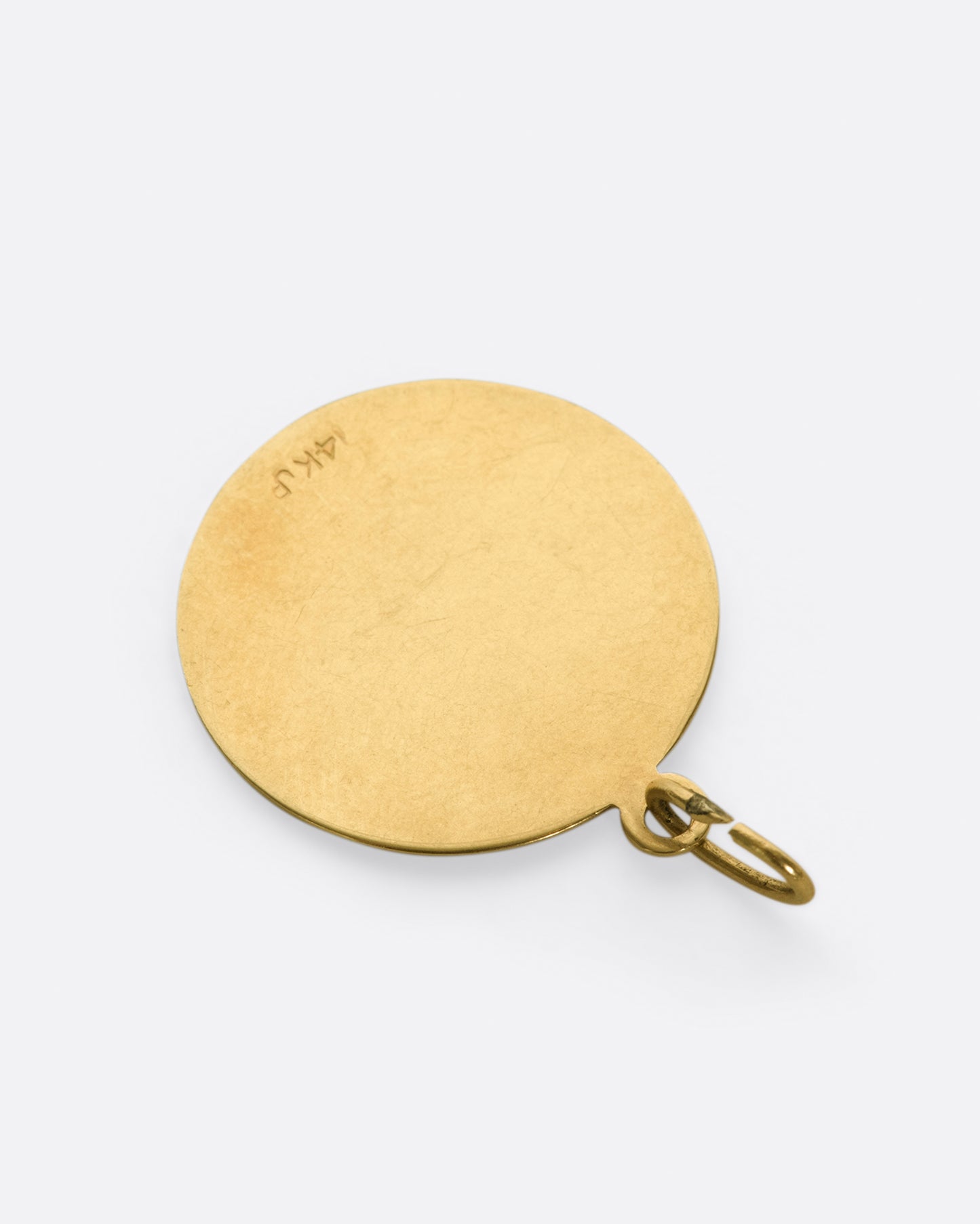 An engine turned zodiac pendant with a blank, polished backside.