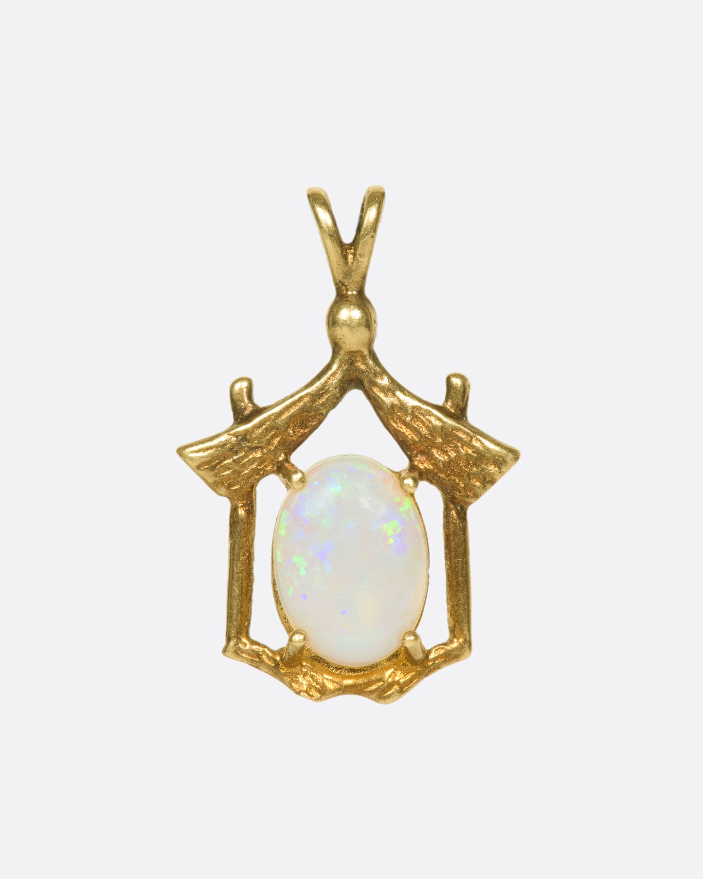 An oval, rainbow opal nestled in a house-like setting.