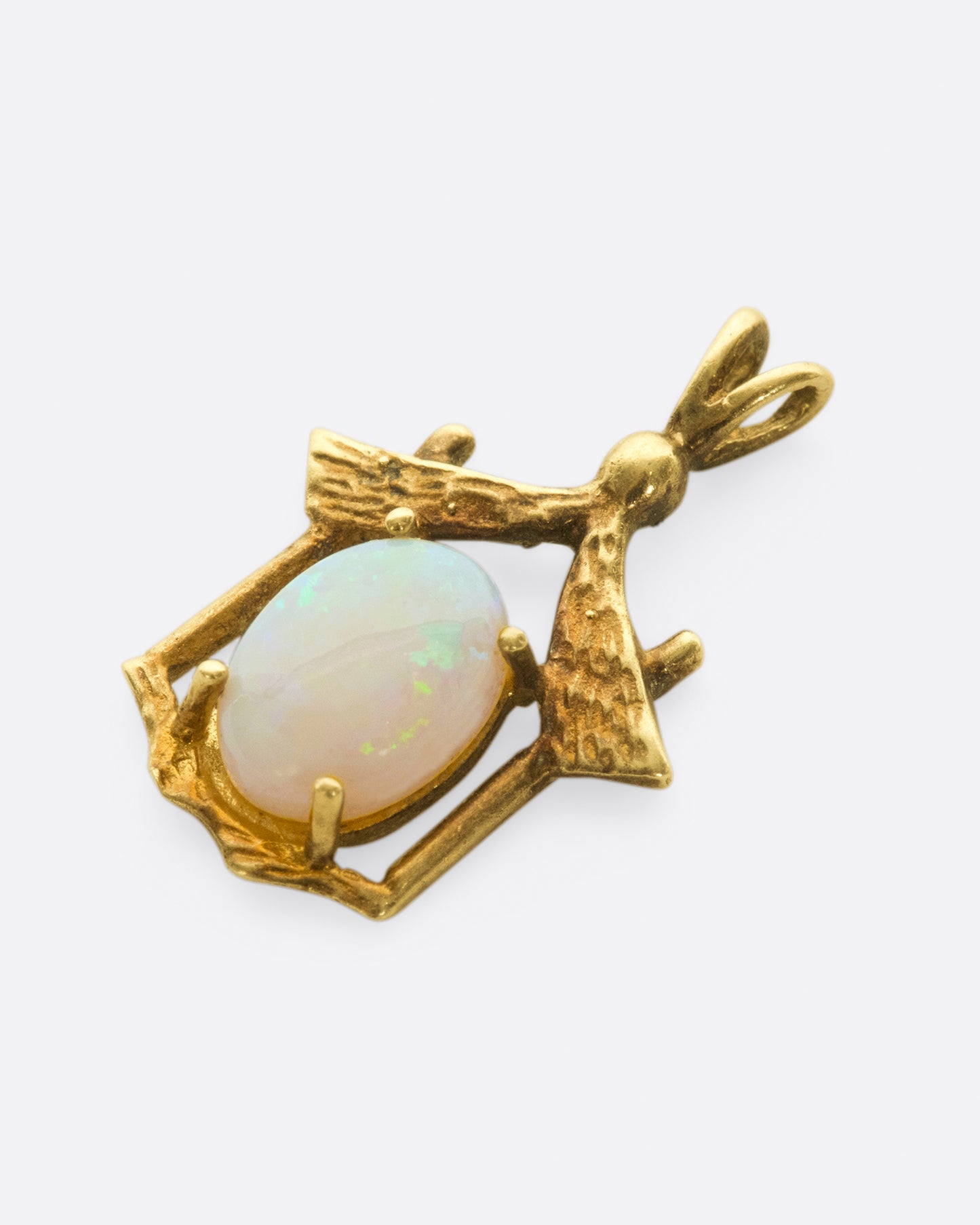 An oval, rainbow opal nestled in a house-like setting.