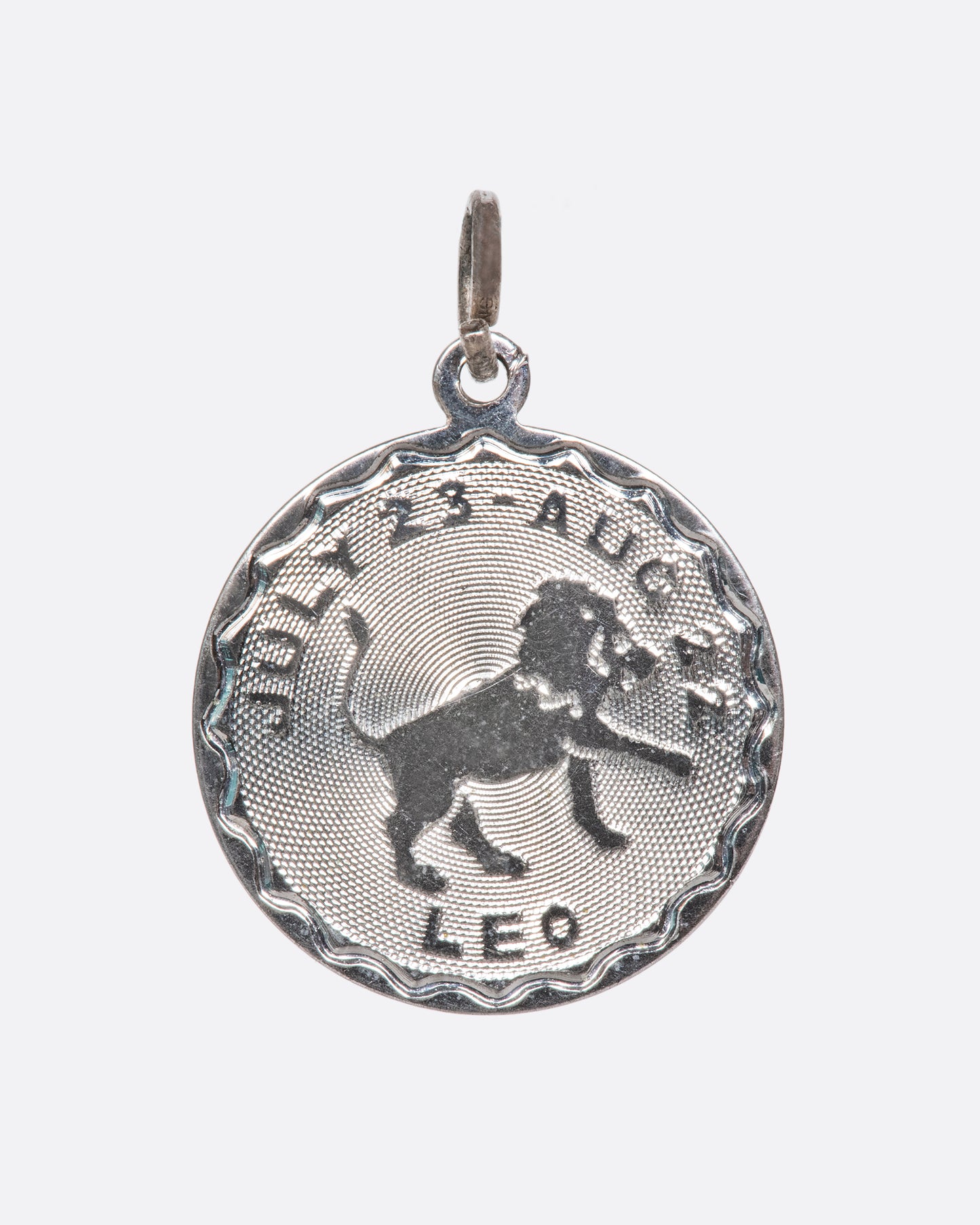 An engine turned pendant featuring the lion and Leo dates.