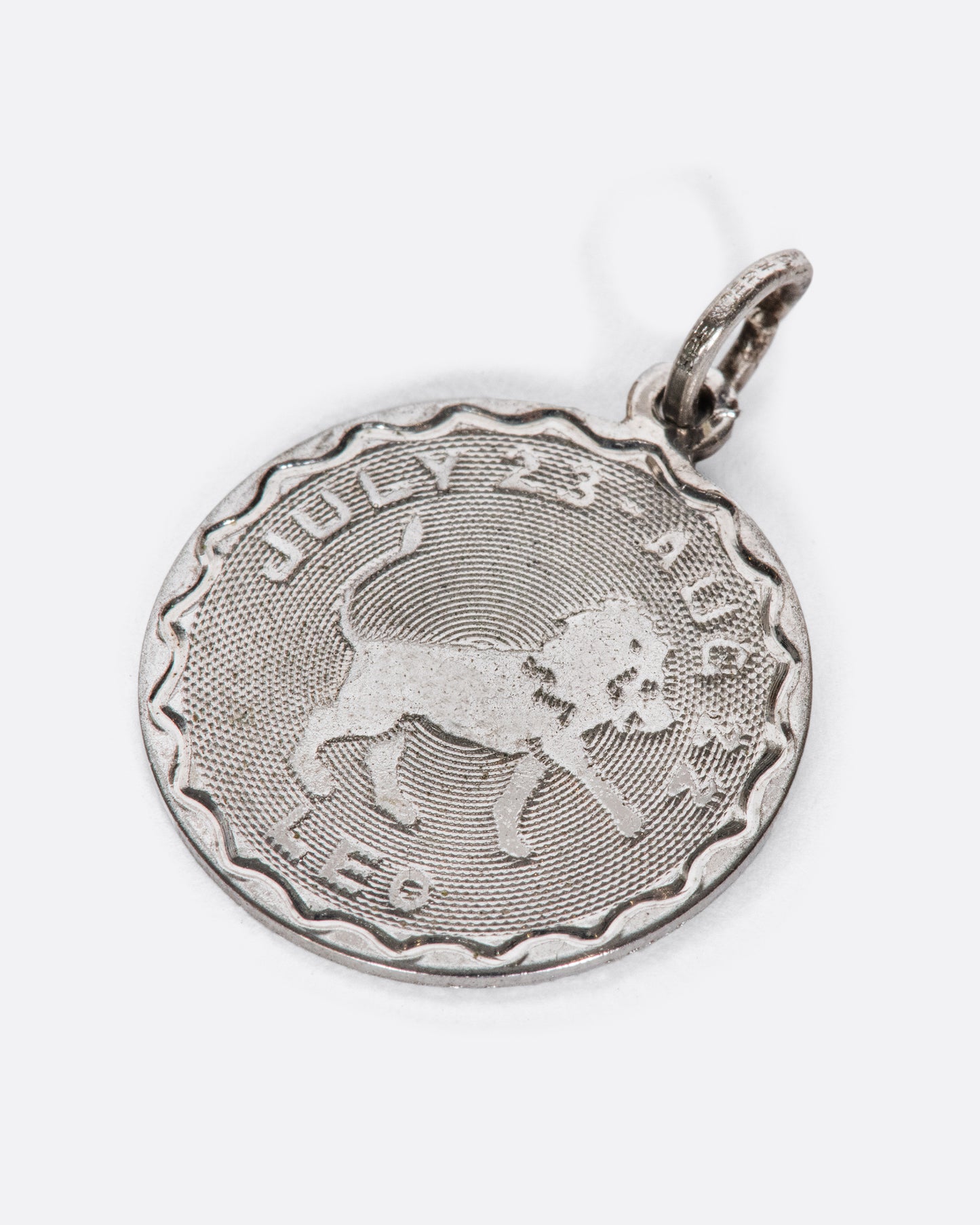 An engine turned pendant featuring the lion and Leo dates.