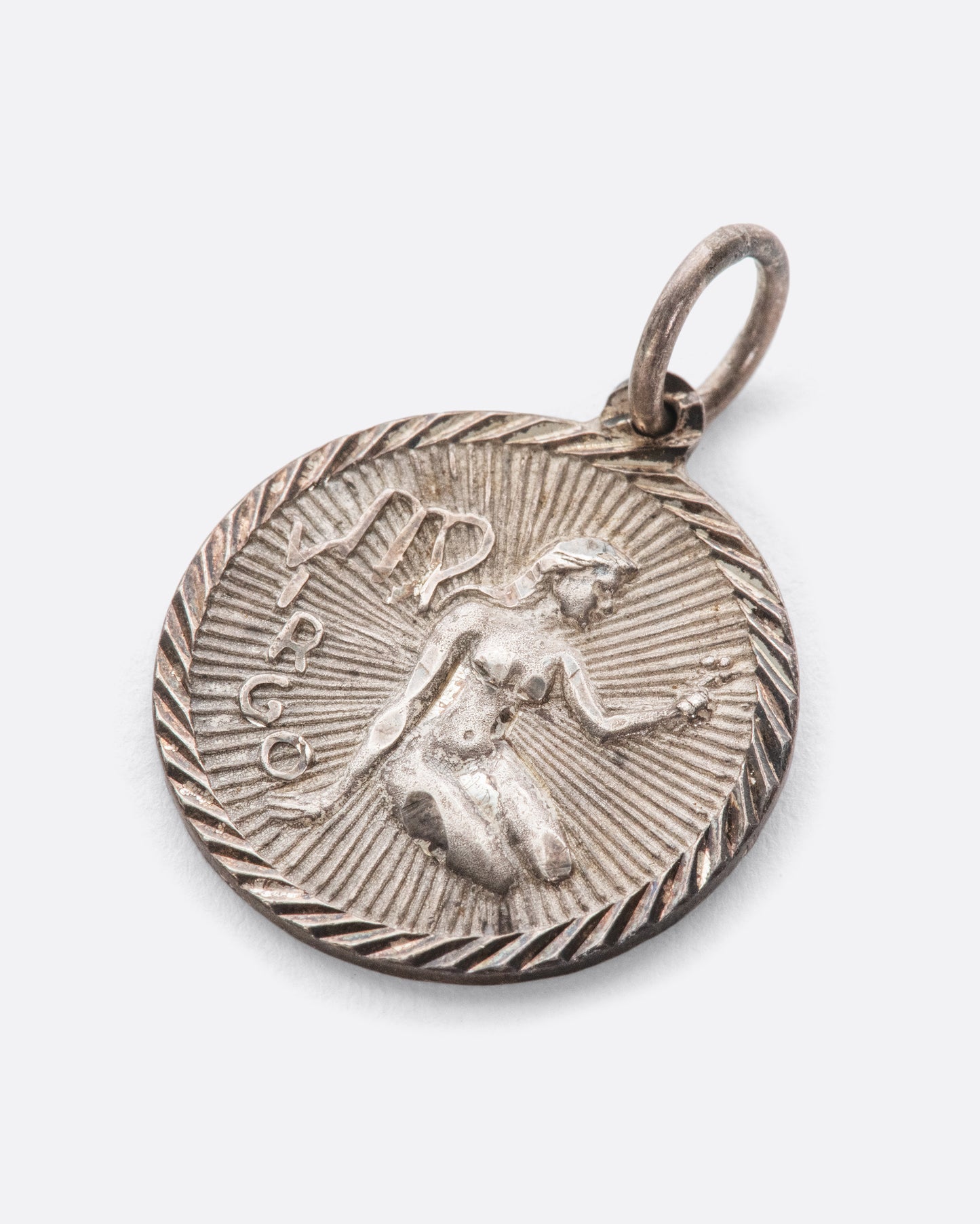 An engine turned pendant featuring the virgin goddess and Virgo symbol.