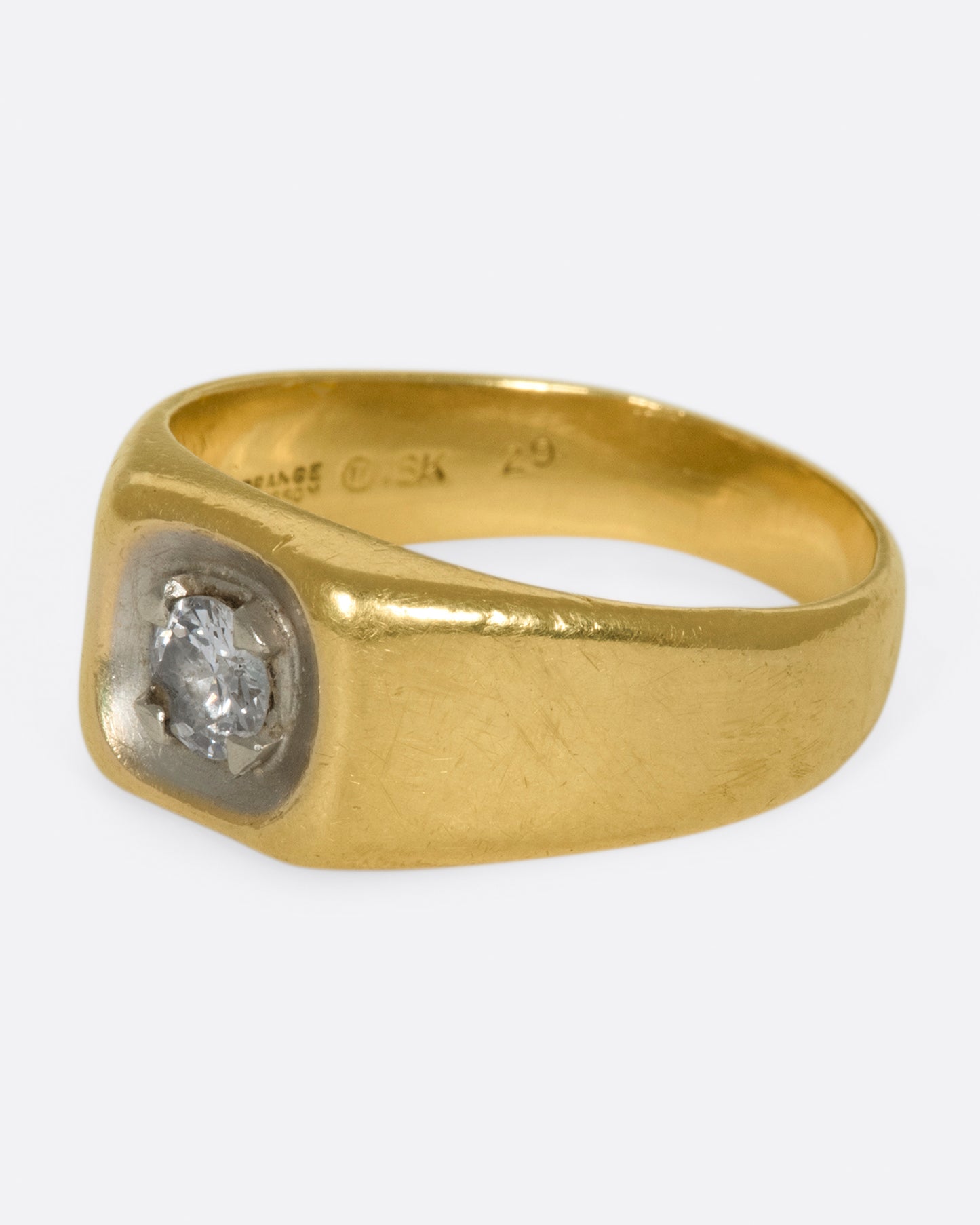 A vintage gold signet ring with a sunken diamond at its center.