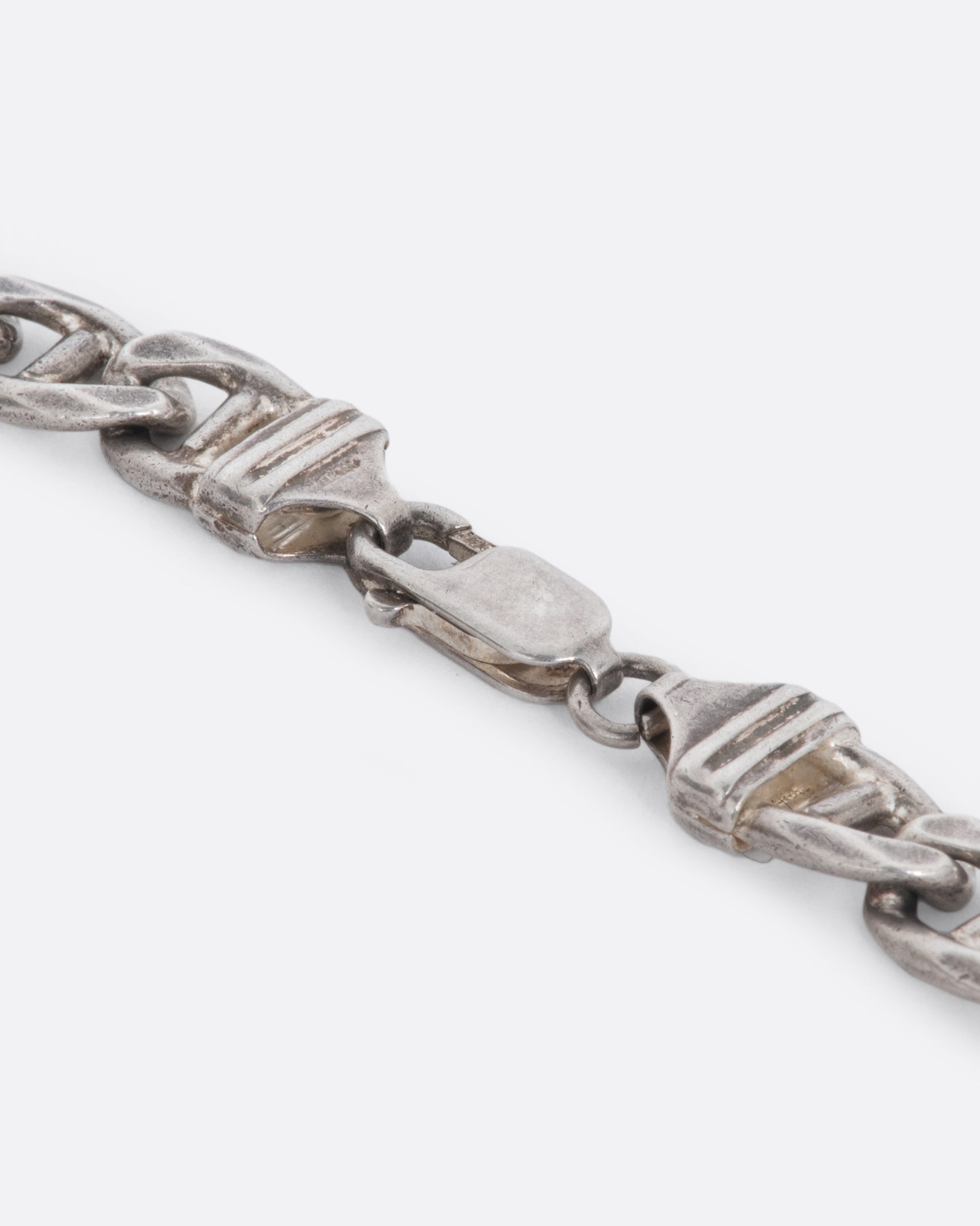 A close up on the clasp of a vintage sterling silver flat mariner chain necklace.