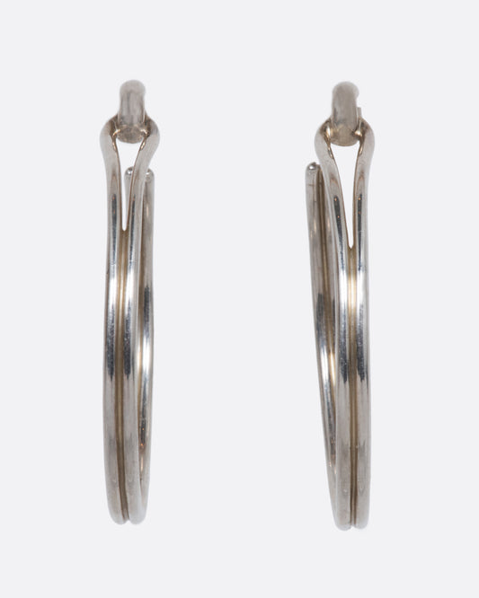 A pair of vintage sterling silver hoop earrings that connect to their posts with what looks like a loop.