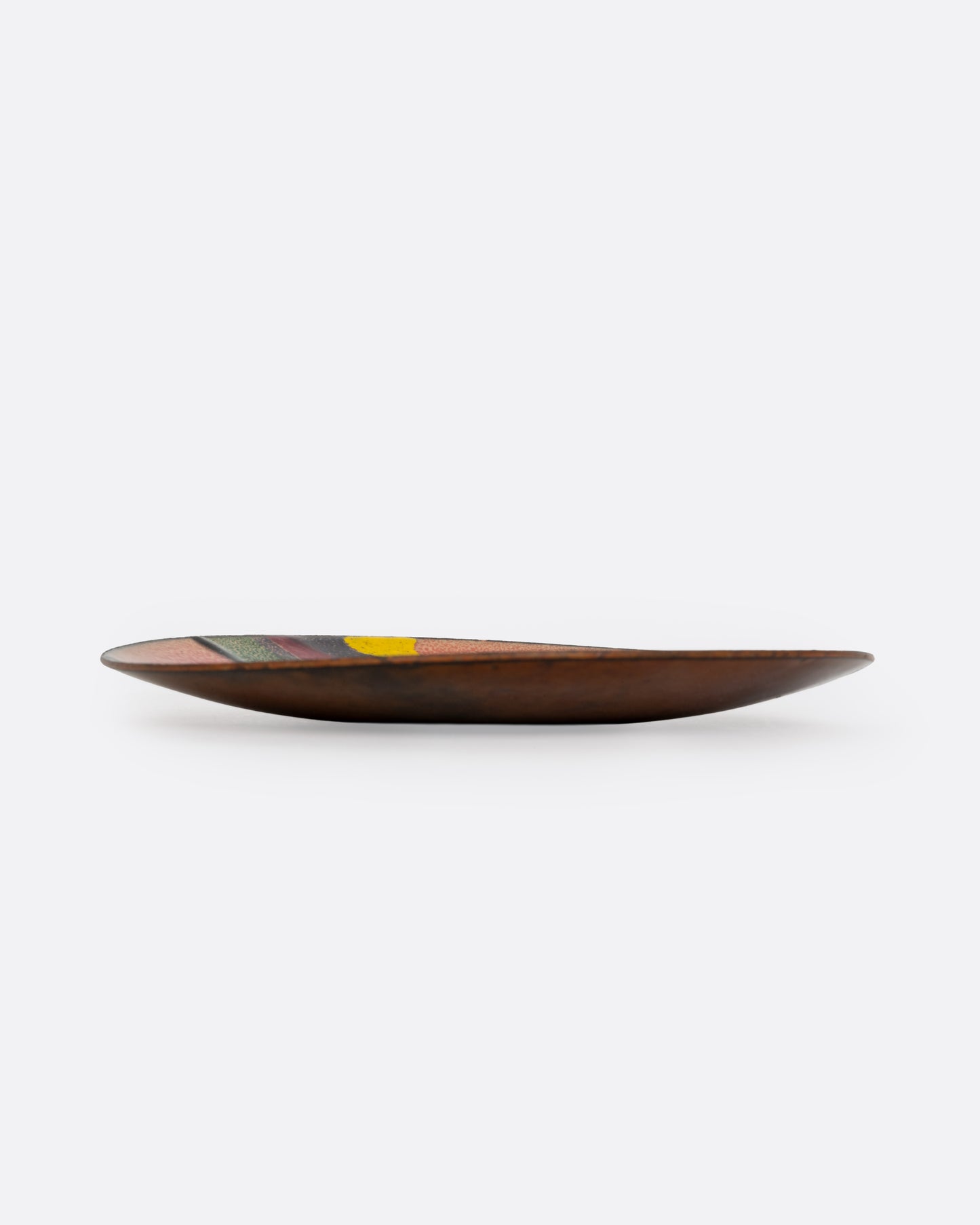 A metal and enamel plate with an abstract graphic design in orange purple, green, and yellow. Shown from the side.