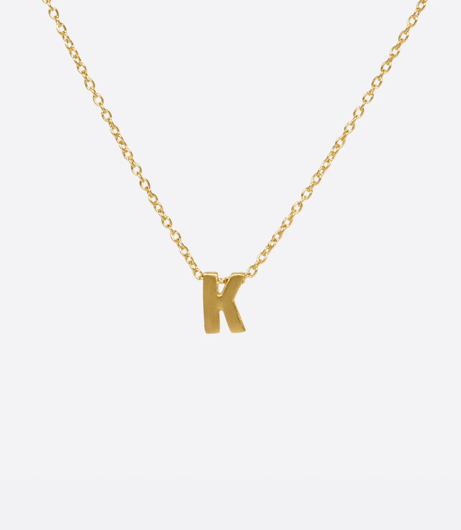 A yellow gold cable chain necklace with a letter K initial pendant. Shown from the front.