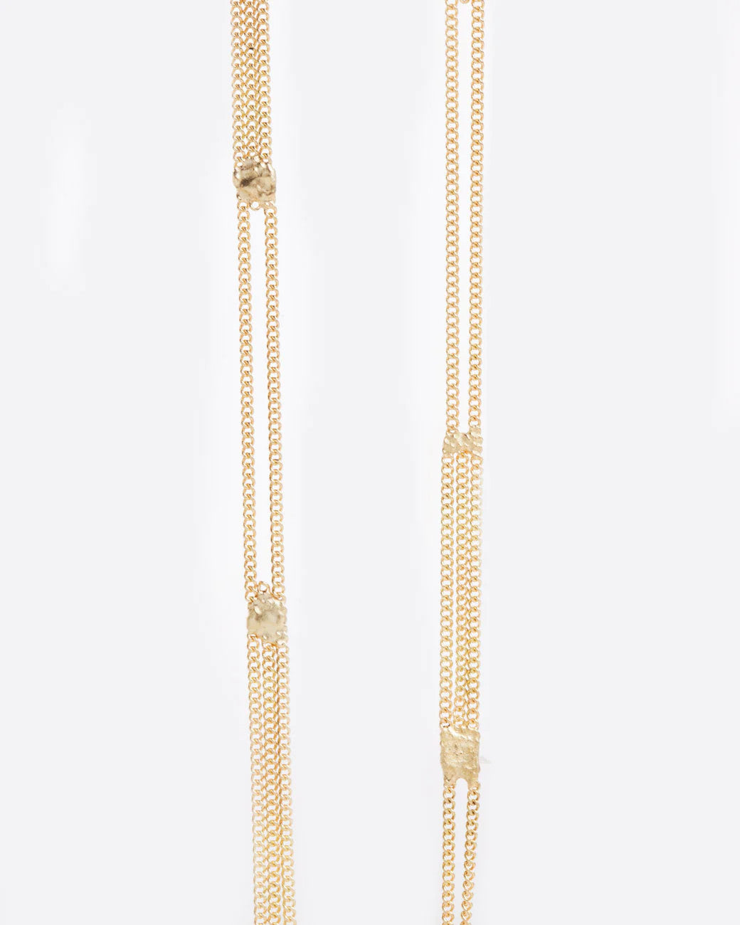 A long yellow gold multi chain necklace with alternating pattern of squares finished with gold solder. Shown close up from the front.