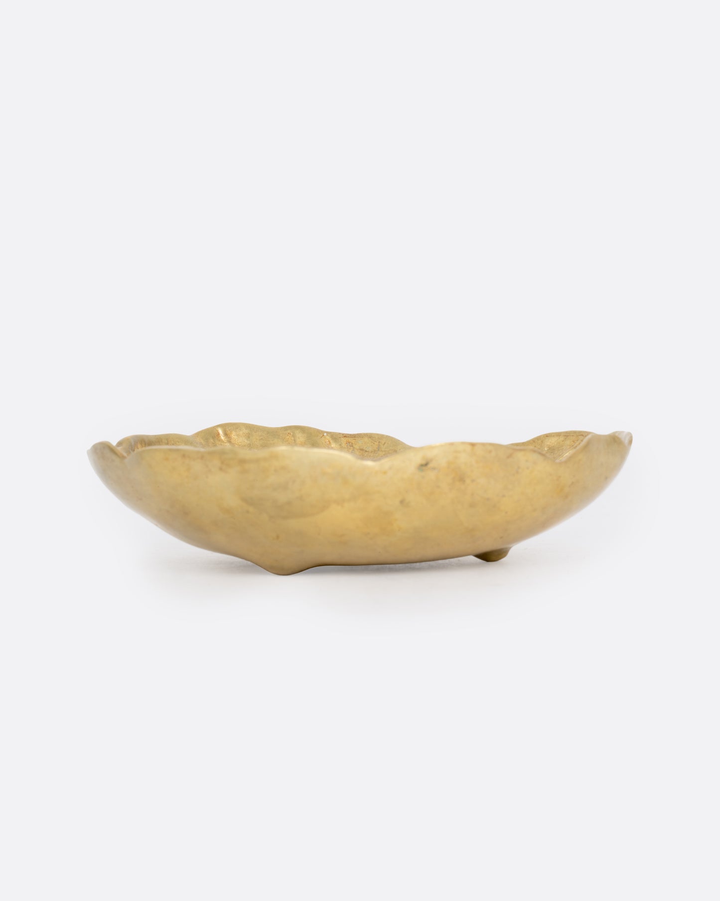 A brass leaf shaped dish, shown from the side.