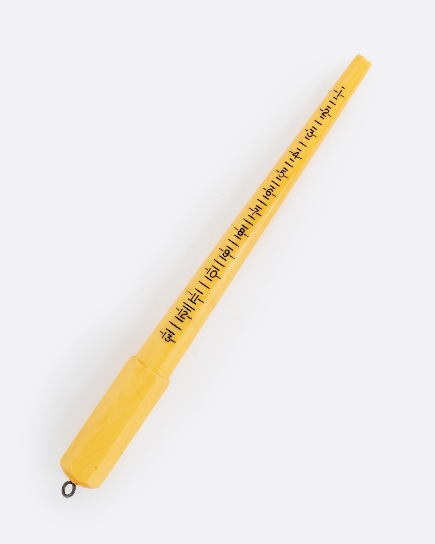 A yellow bakelite mandrel with a metal loop on one end and measurements on its front. Shown from the front.