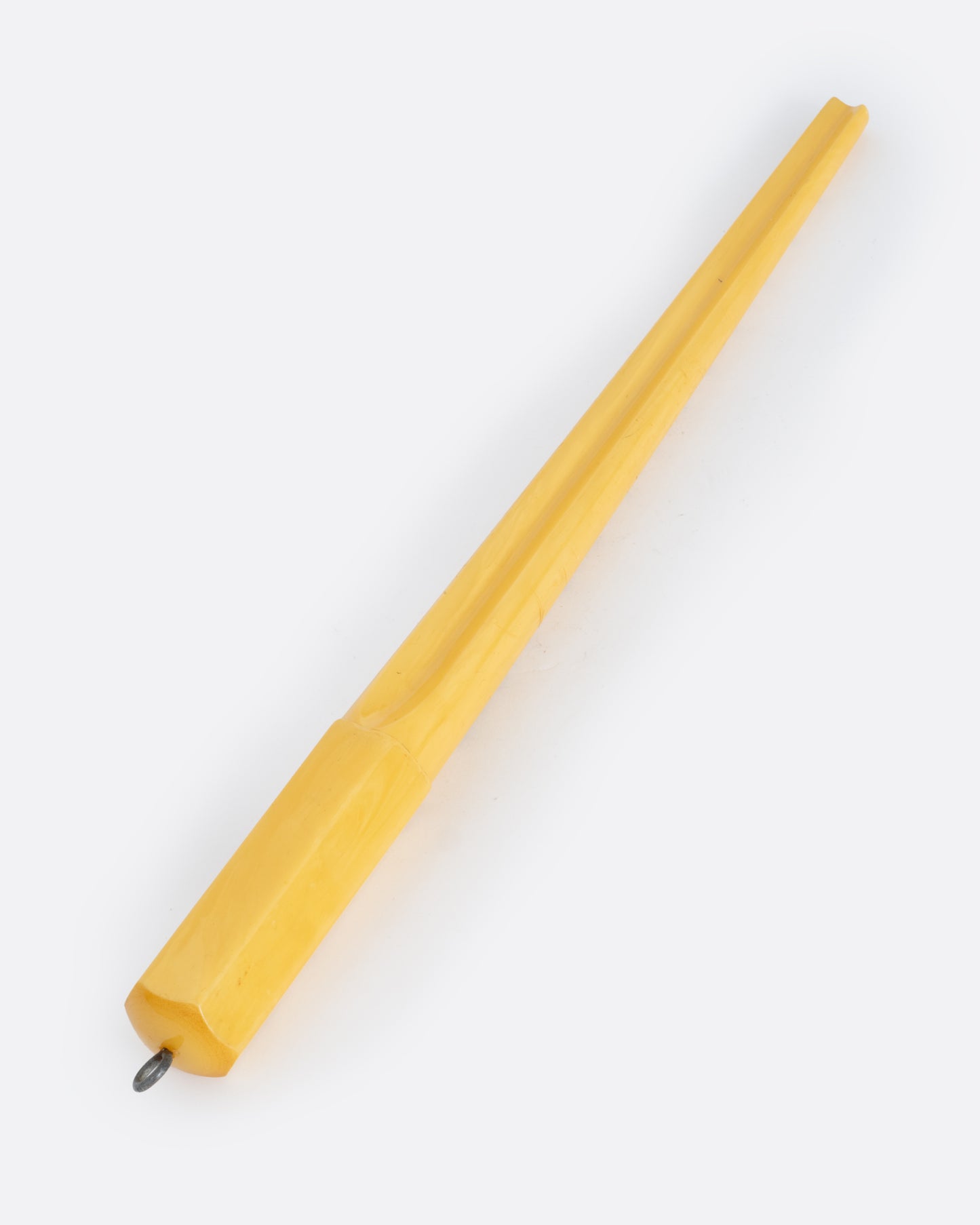A yellow bakelite mandrel with a metal loop on one end and measurements on its front. Shown from the back.