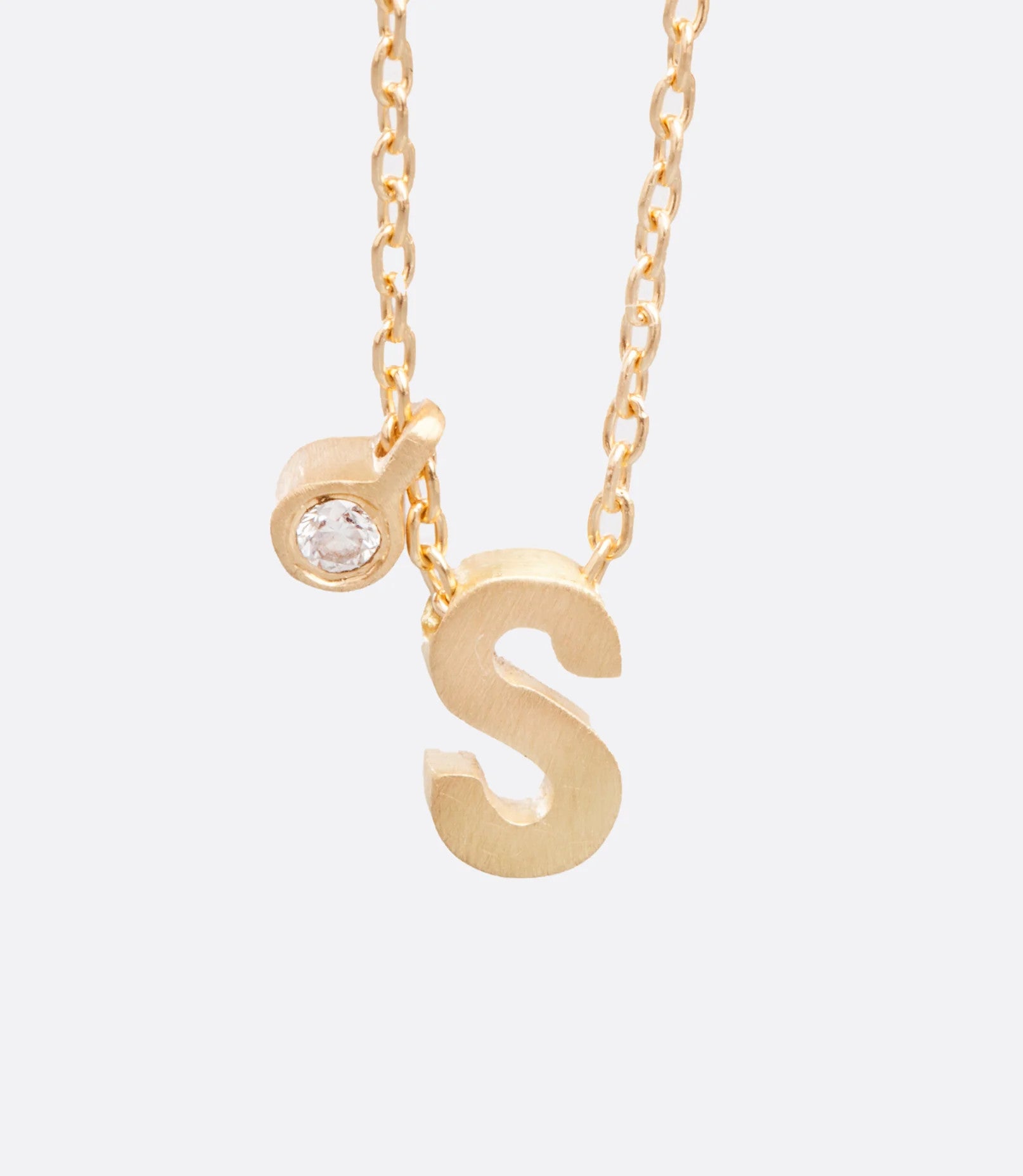 A yellow gold cable chain necklace with a letter S initial pendant. Shown from the front with a separate diamond tag.