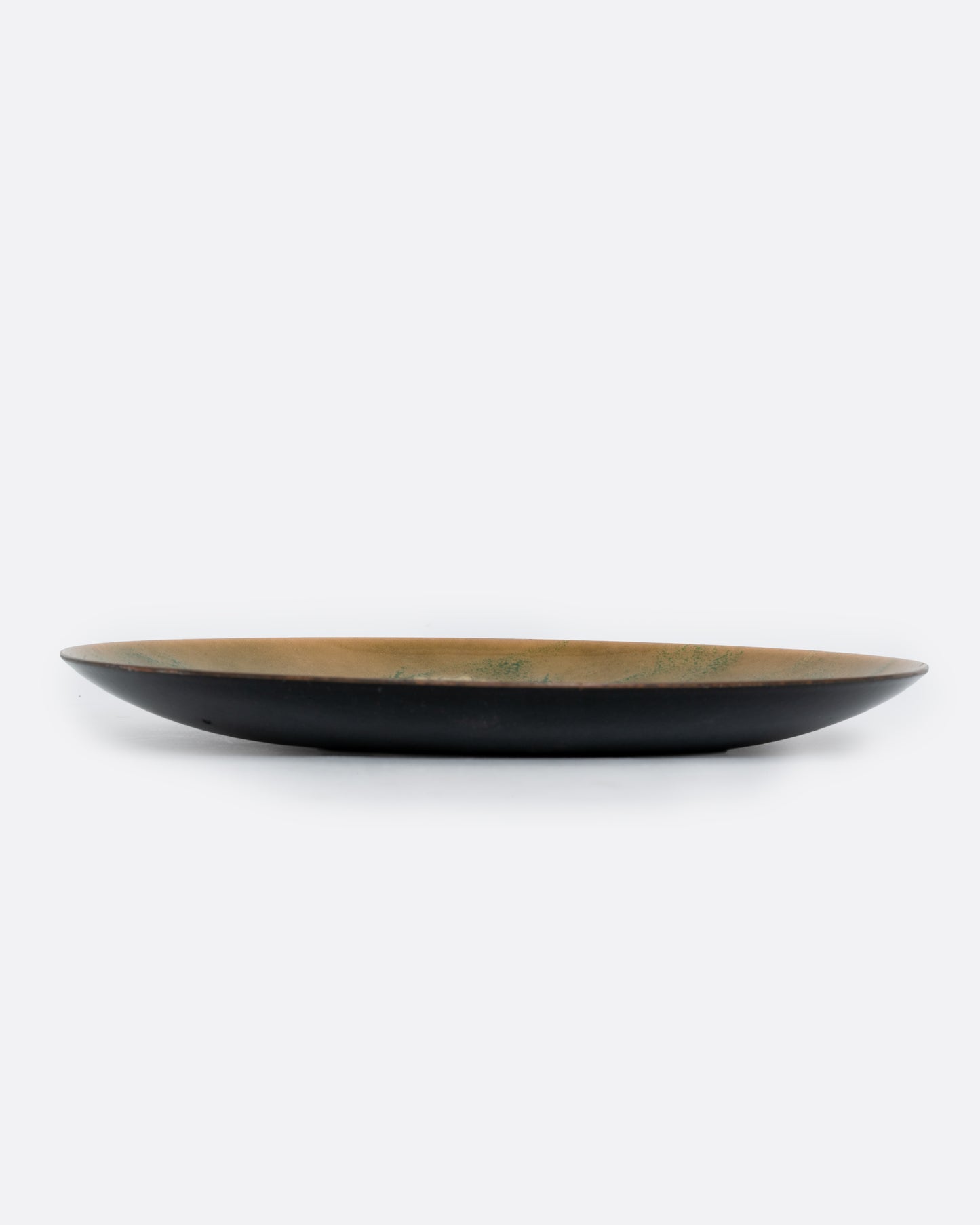A metal and enamel plate with an abstract cluster design in green and yellow. Shown from the side.